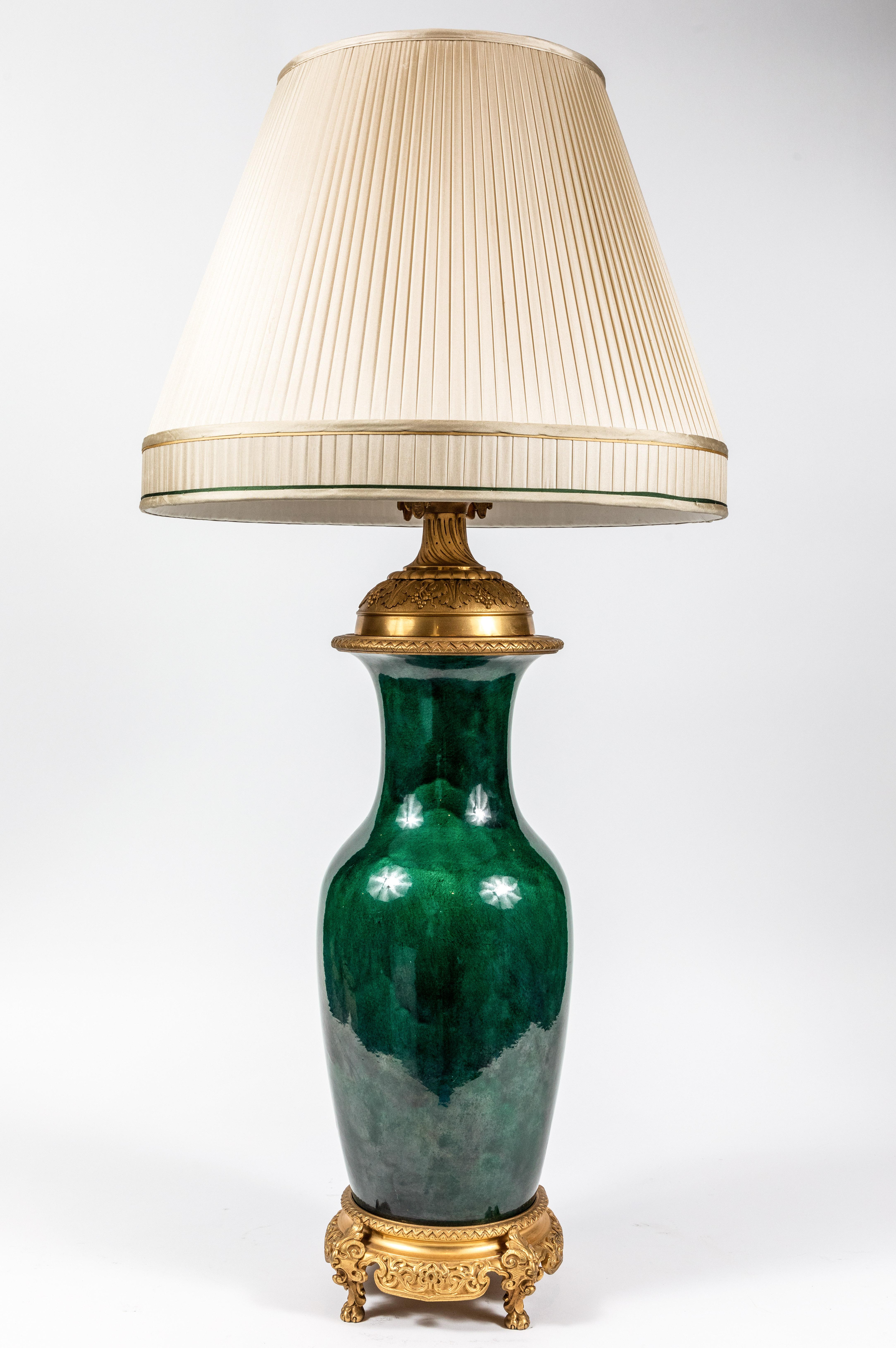 Pair of fine, large, French, green, glazed lamps with superior, molded, gilt bronze mounts. Each capped by custom, silk shades. Formerly gas lamps, now wired for U.S. current. 

Note: Measurements including shade: 38 in. height x 18 in. diameter.