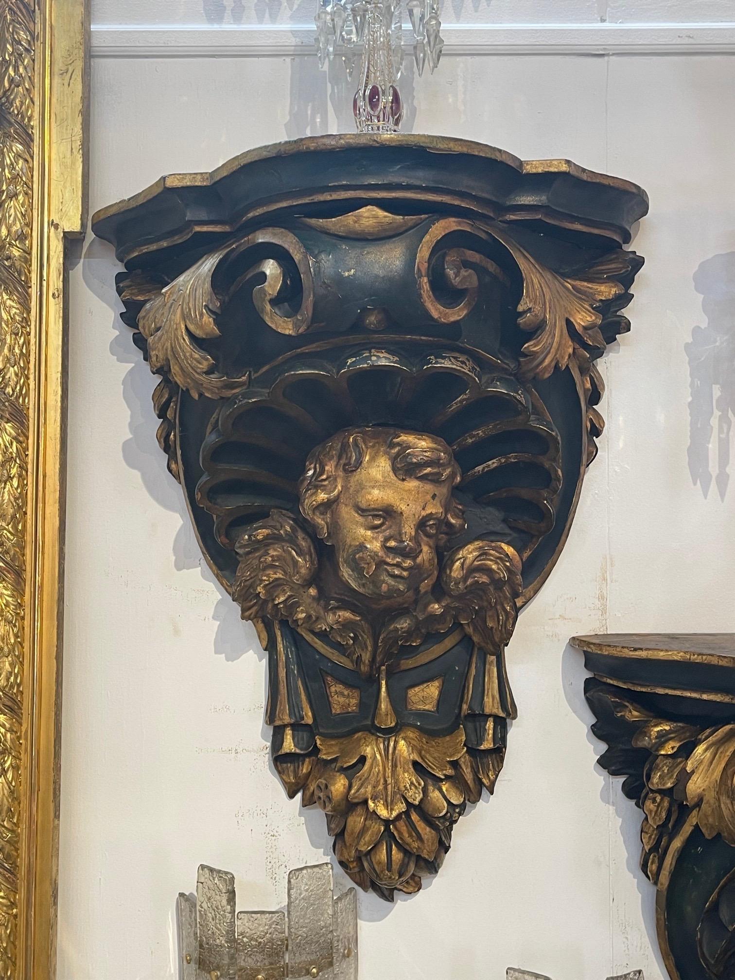 Large scale beautiful pair of 19th century carved and parcel gilt cherub wall brackets. A lovely decorative accent!