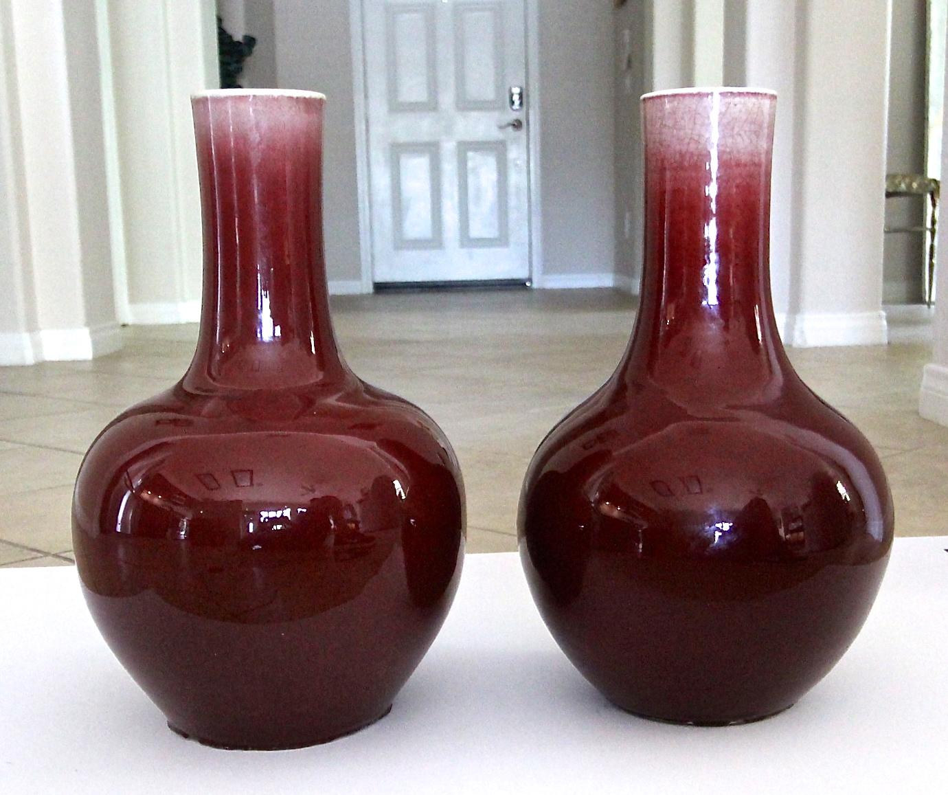 Pair of (two) large late 19th century (possibly earlier) ‘sang de boeuf’ or oxblood glazed porcelain Chinese vases. The vases are globular form surmounted by a slender neck with soft crackled glaze throughout. Later hole drilled in each and used as