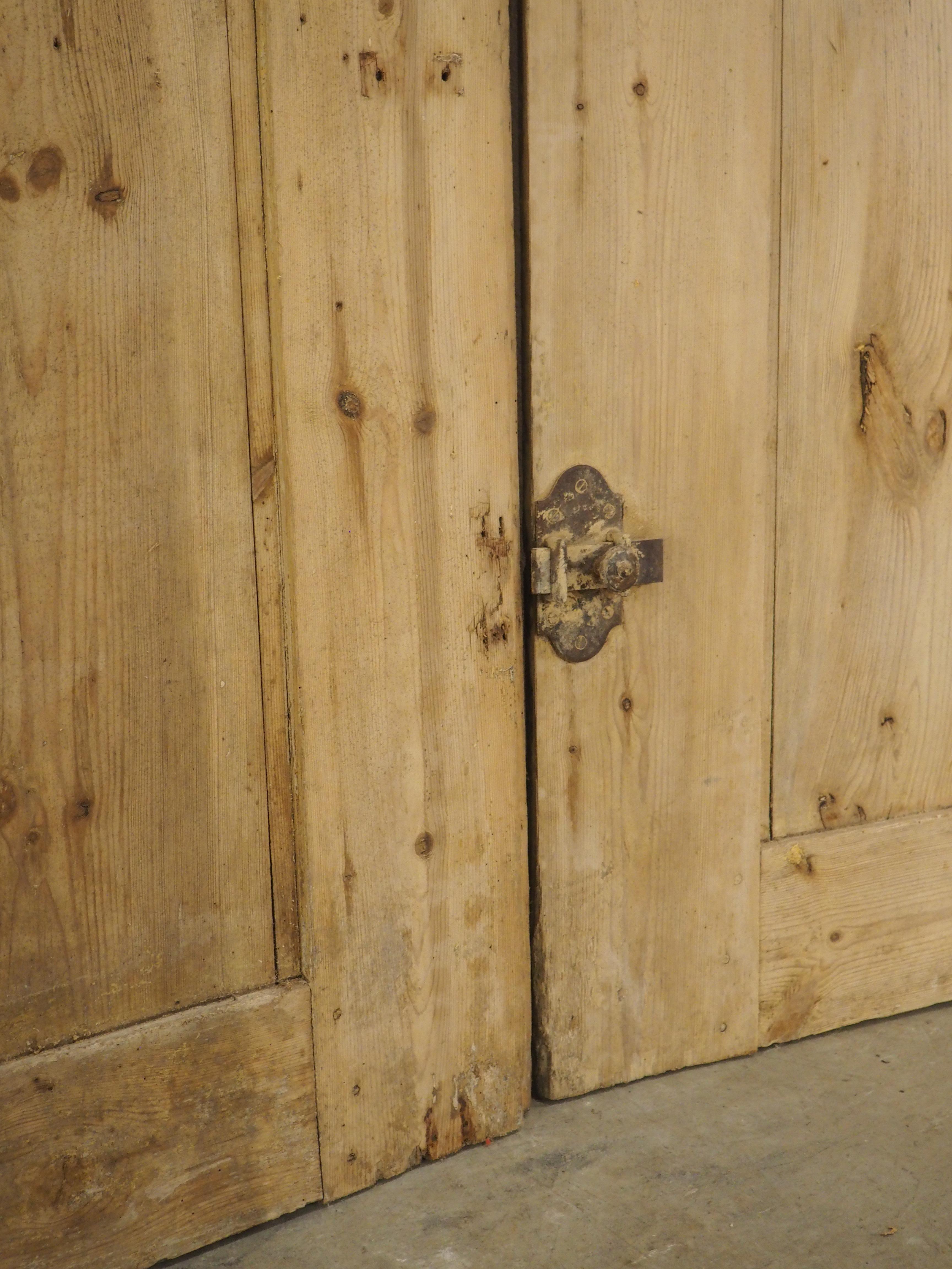 A well-carved pair of architecturals, dating to the 1800s, these large French doors feature five panels of motifs in the style of the Gothic period. The top two panels, which are aligned vertically, are adorned with arcading that is topped by barbed