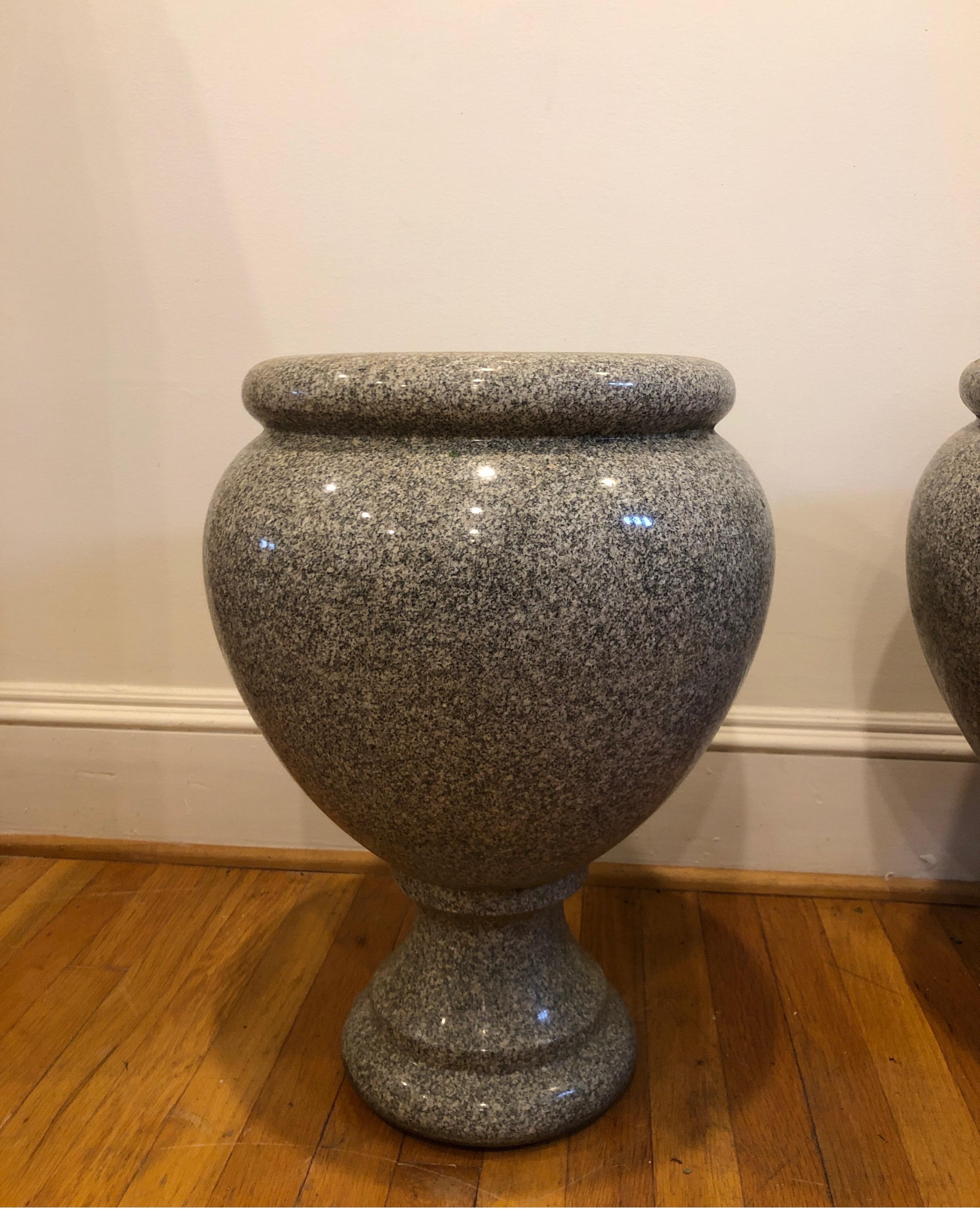 Gorgeous pair of large scale granite urns. Measure approximate 21.5 height x 16 width x 16 depth.
Almost 10 inch opening at top.
Have been used as planters.

The body has Classic elegant shape with rim around the edge. 
Mix of grays, creams and