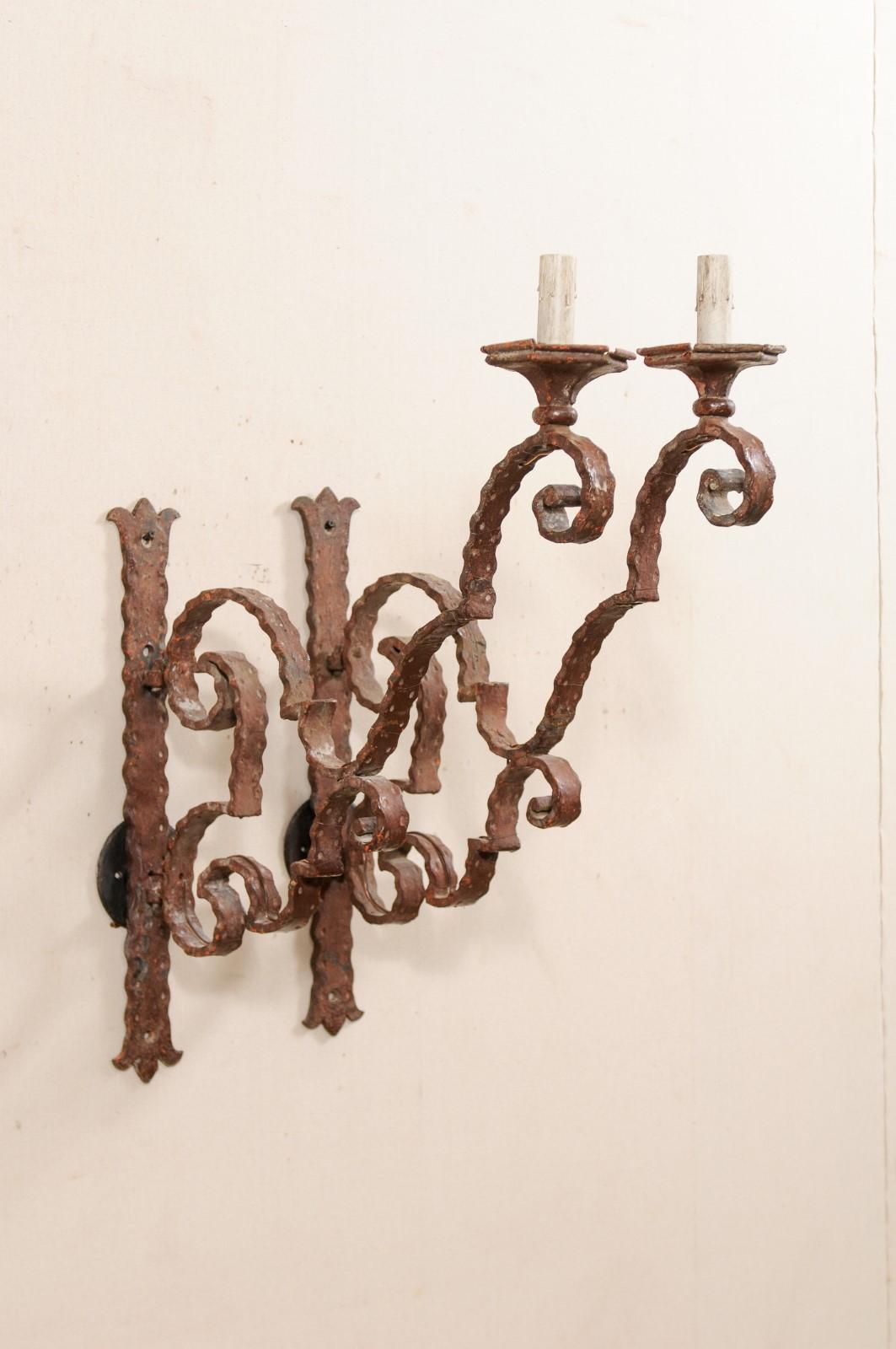 A pair of Italian single light iron sconces, long arm extensions, from the 19th century. This pair of antique sconces from Italy each feature a large-sized single arm, comprised of scrolling armature, with nice, outward projection, with a single