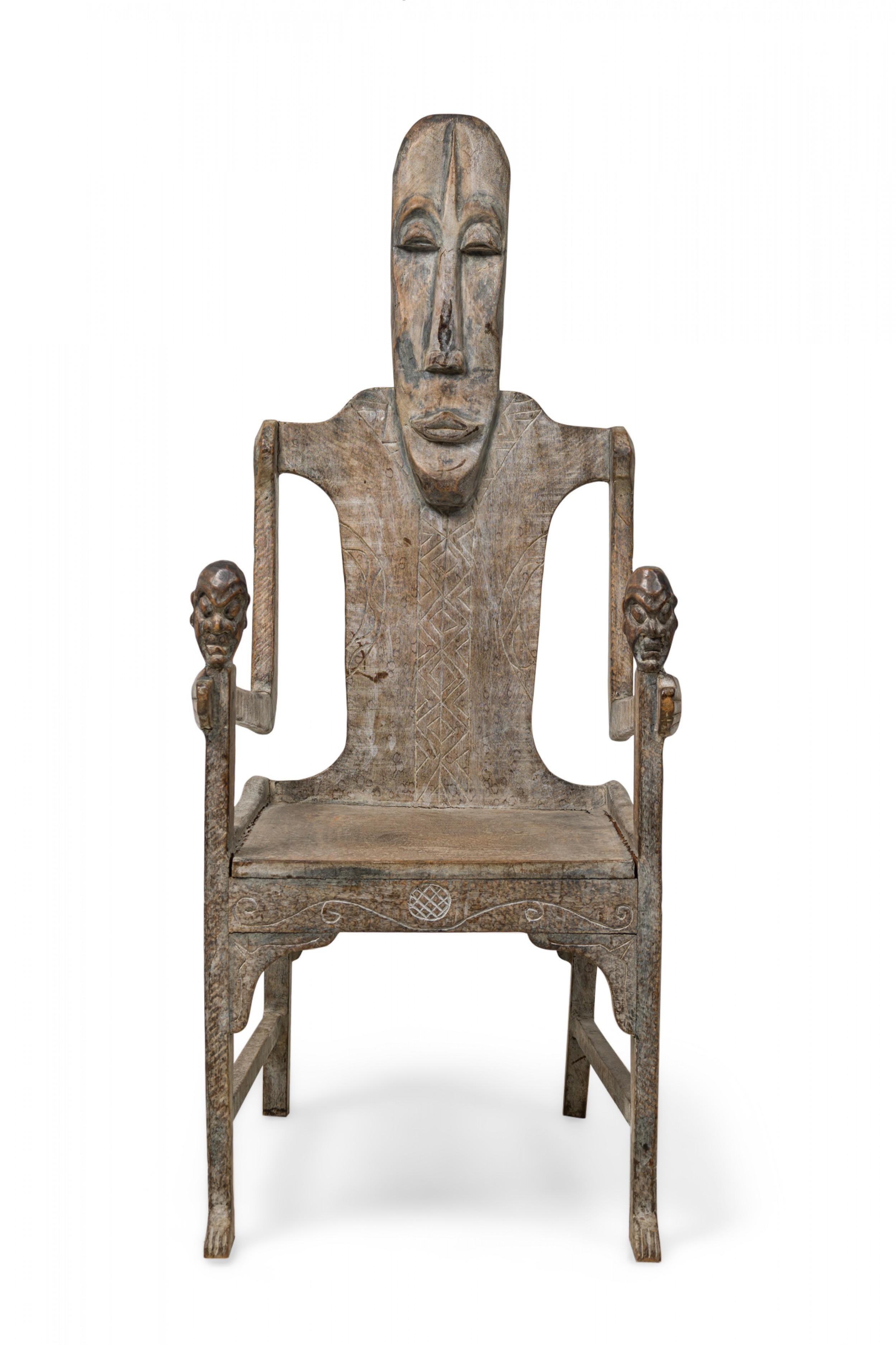 PAIR of Large African (Early 20th Century) rootwood armchairs with carved figural backs, both grasping mask staffs as front supports, with incised decorative patterns, ending in 2 carved front feet. (PRICED AS PAIR).