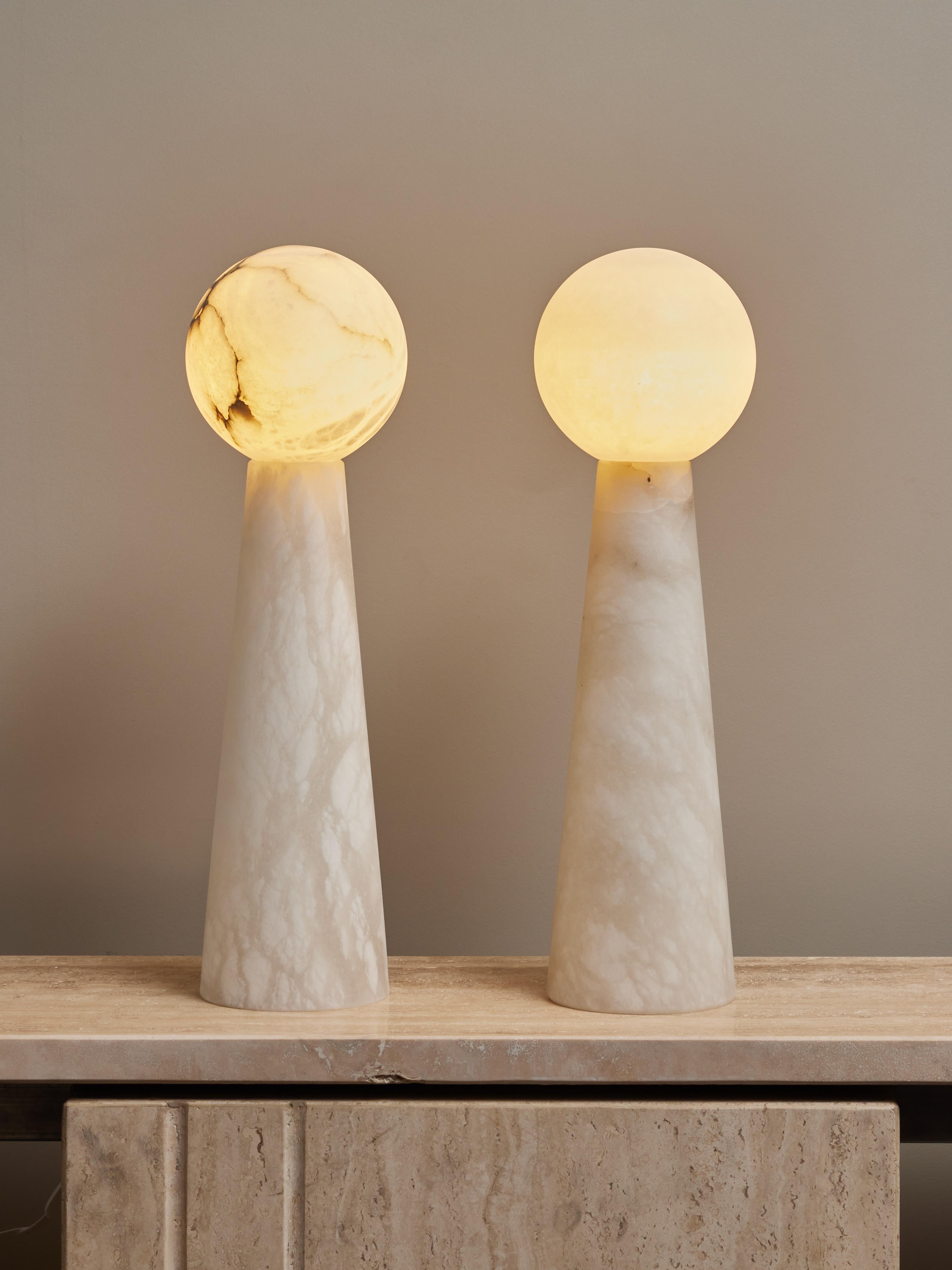 Paire de lampes de table constituées de deux pièces d'albâtre, un pied conique, surmontées d'un globe diffusant la lumière. 