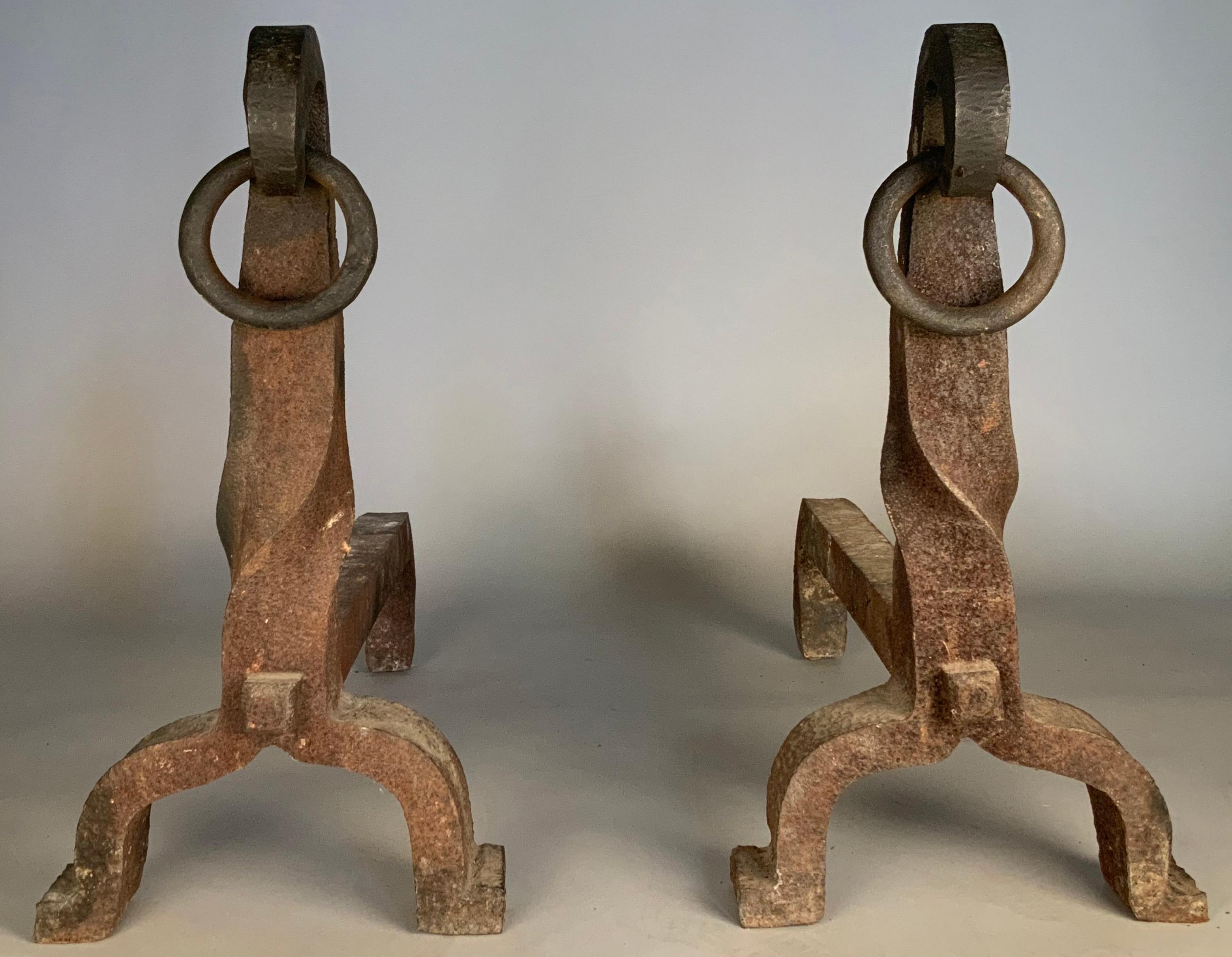 a very large pair of antique 1920's cast iron andirons, with twisted stems terminating in a curled top with a loose iron ring. Very heavy and very well made. Wonderful scale and proportions.