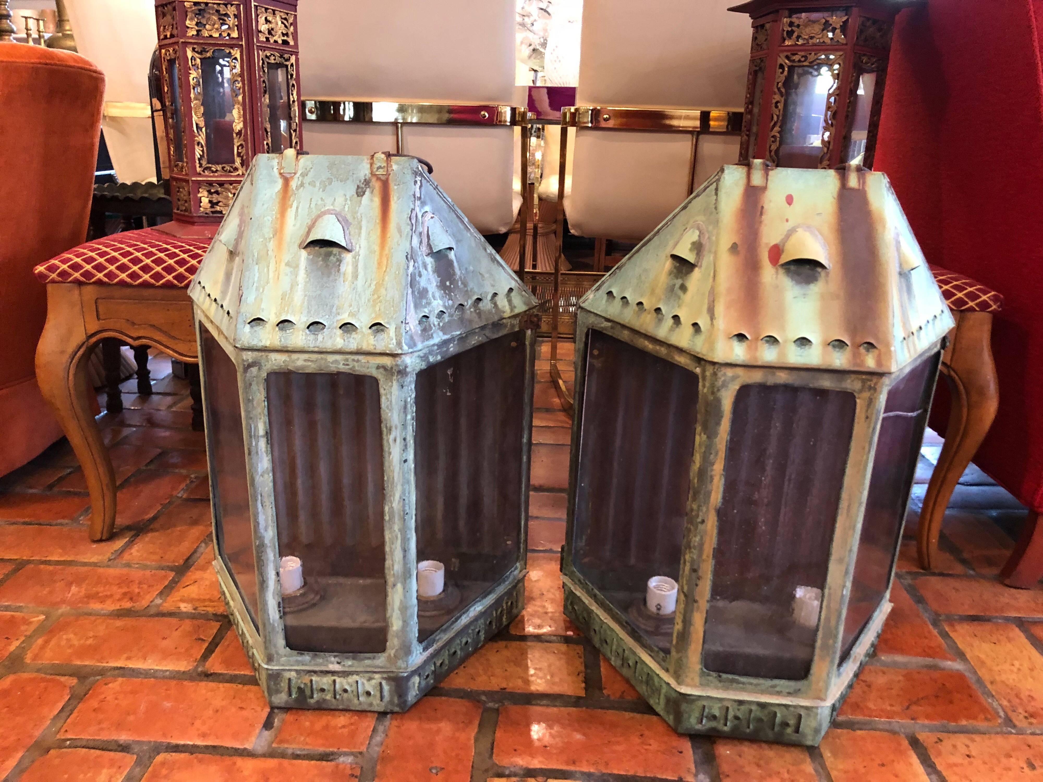 Pair of large antique copper lanterns. Wonderful aged verdigris patina. Heavy and substantial. Probably originally
gas lit but now electrified with two sockets per lantern. Original thick hand blown bubble glass. One panel of one lantern has a very