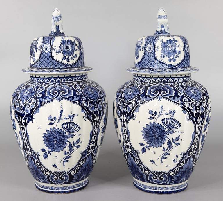 A lovely pair of Mid-20th Century Dutch Delft faience lidded ginger jars by well known Dutch maker, Petrus Regout in Maastricht, Holland at the Royal Sphinx factory. Maker's marks on the reverse. These stunning vases are a nice large size with a