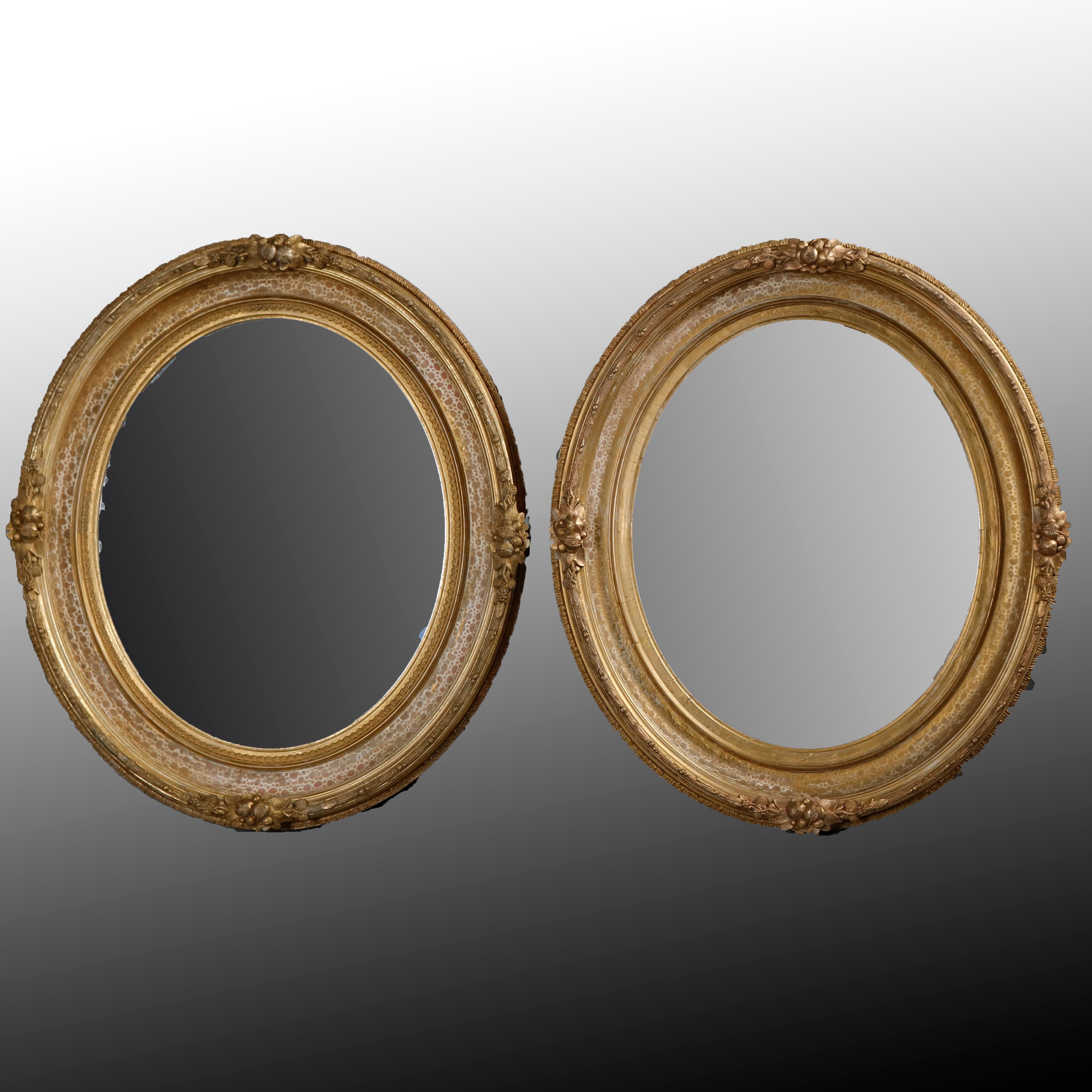 A pair of large and antique French Louis XIV wall mirrors offer giltwood frame in oval form having modeled finish and fruit and nut foliate elements, circa 1870

Measures: 29.75