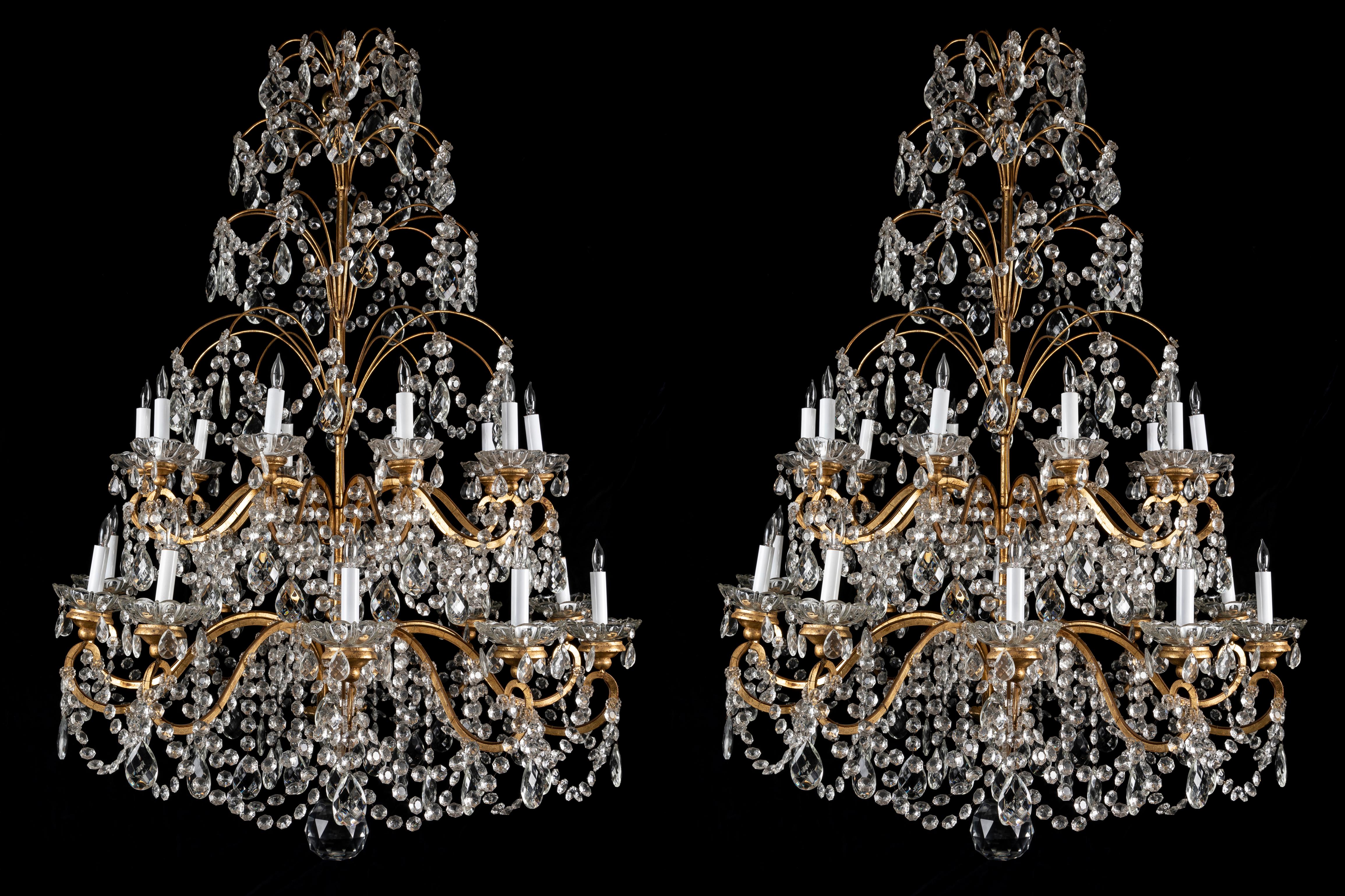 A gorgeous pair of very large French Louis XVI style 20 light multi tier gilt bronze , wood and crystal chandeliers of superb workmanship. Each twenty light chandelier is embellished with scrolled arms and adorned with beautiful circular glass