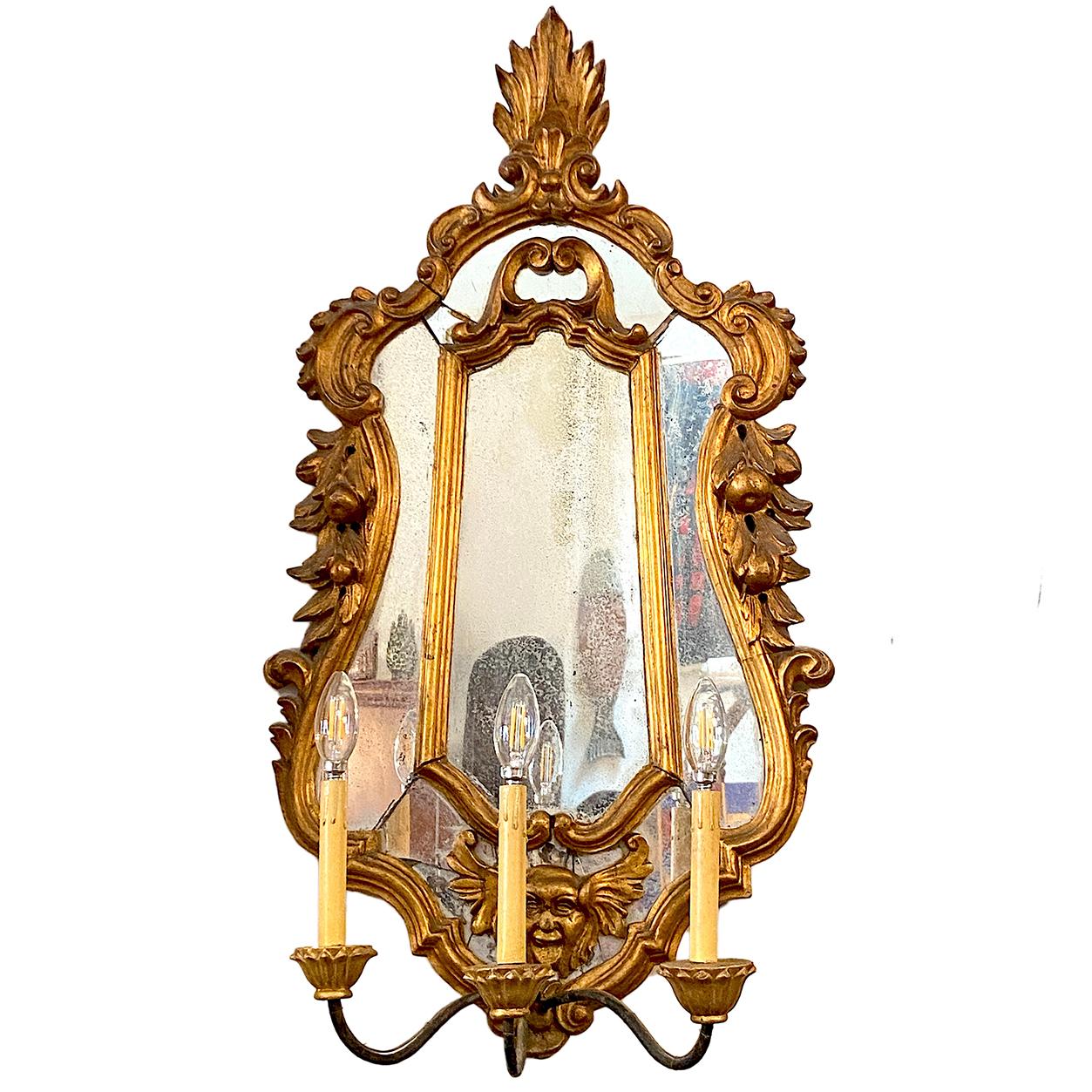 A pair of circa 19th century Italian gilt wood sconces with antique mirror backplate and three-light iron arms.

Measurements:
Height: 38