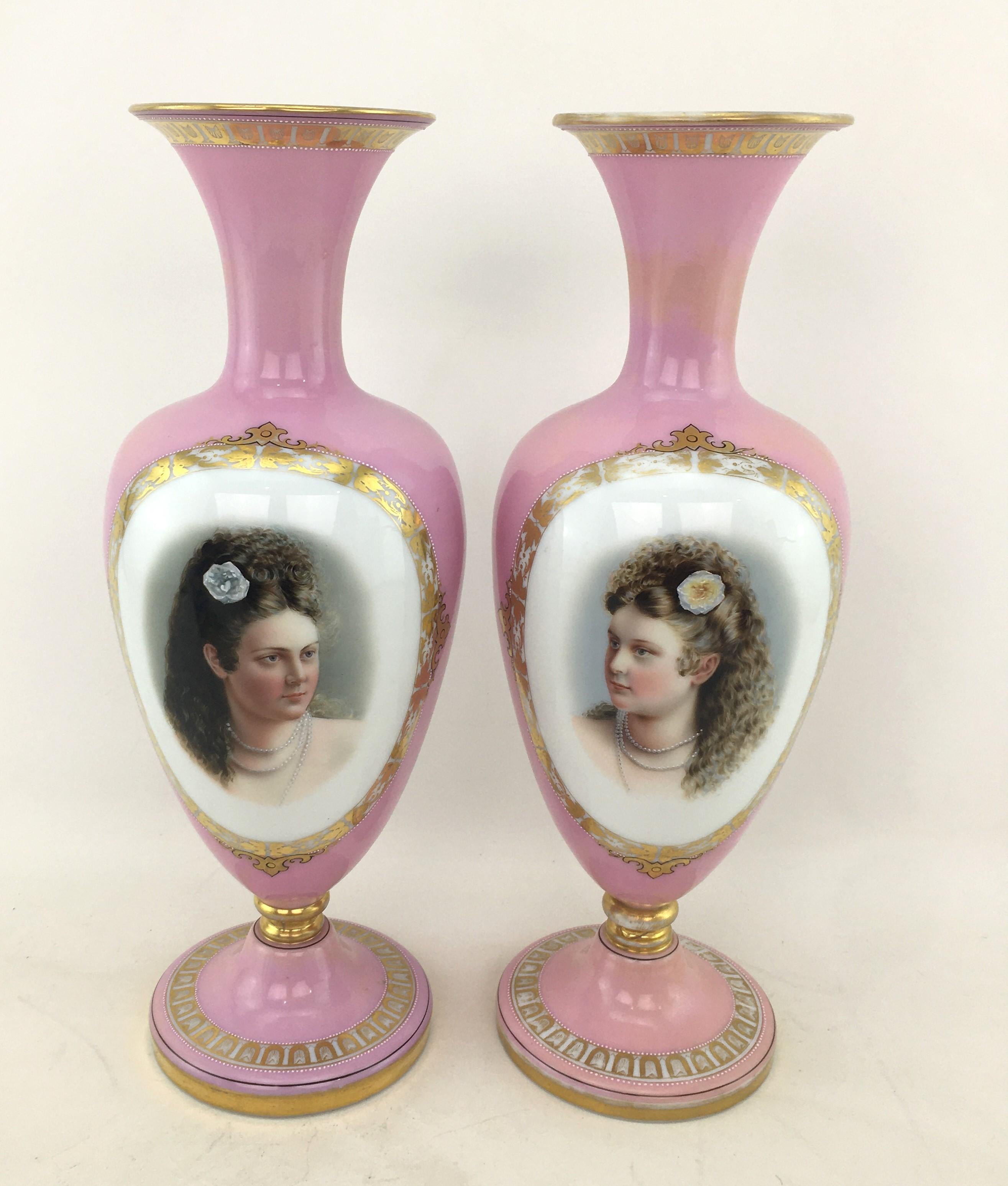 This pair of antique vases are unsigned, but presumed to have originated from Austria and date to approximately 1900 and done in the Victorian style. The vases are composed of cased glass with pink over white with a lustre overglaze and feature a