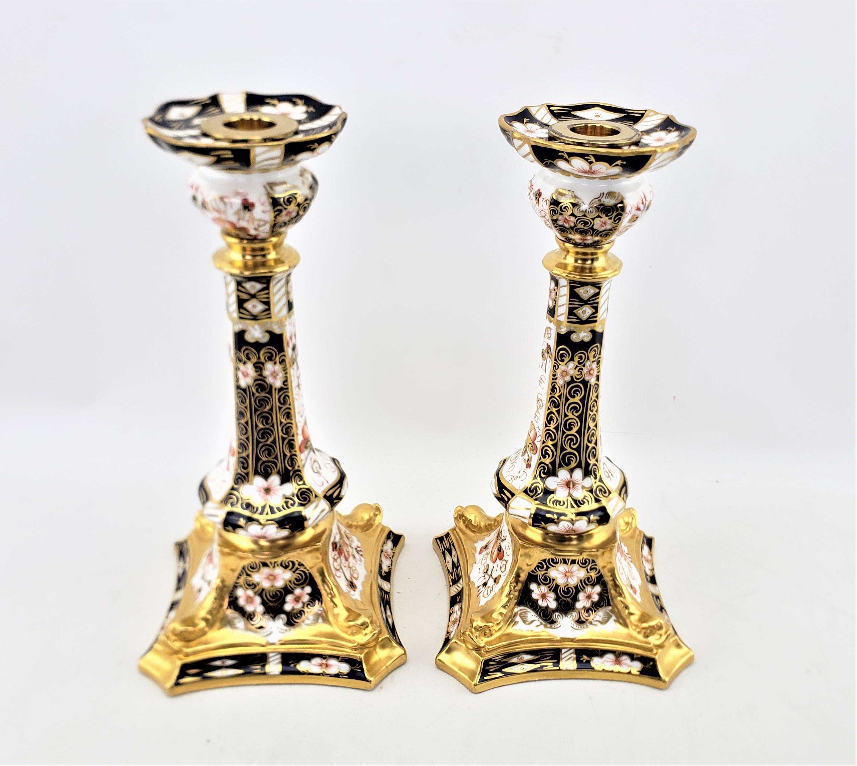 This pair of large candlesticks was made by the highly renowned Royal Crown Derby factory of England in approximately 1920 in their traditional 2451 Imari pattern. The candlesticks are done in fine bone china with a white ground, and hand-painted in