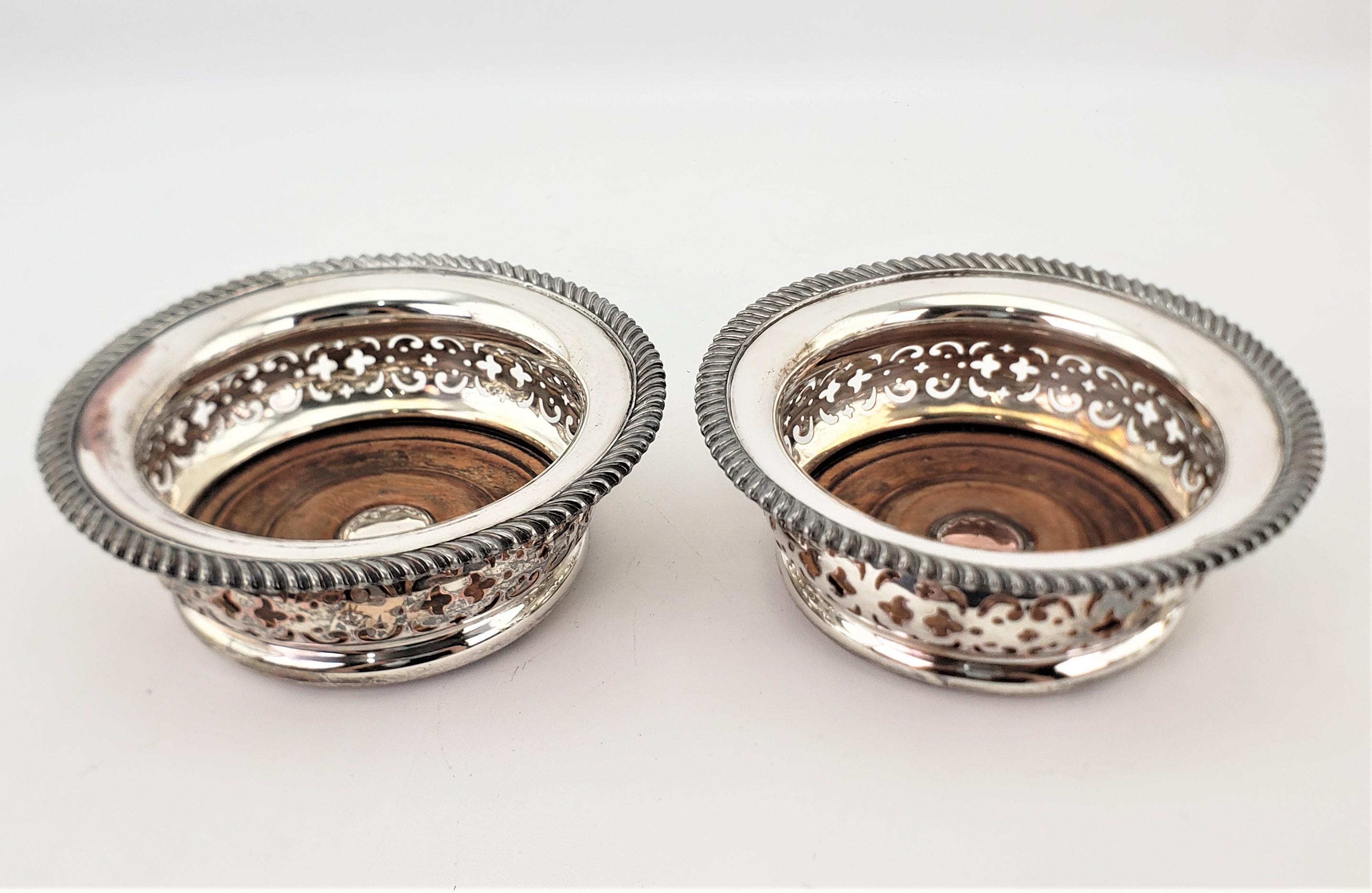 This pair of matching silver plated bottle coasters are unsigned, but presumed to have originated from England and dating to approximately 1890 and done in the period Victorian style. The coasters are large, and have a nice rope styled decoration