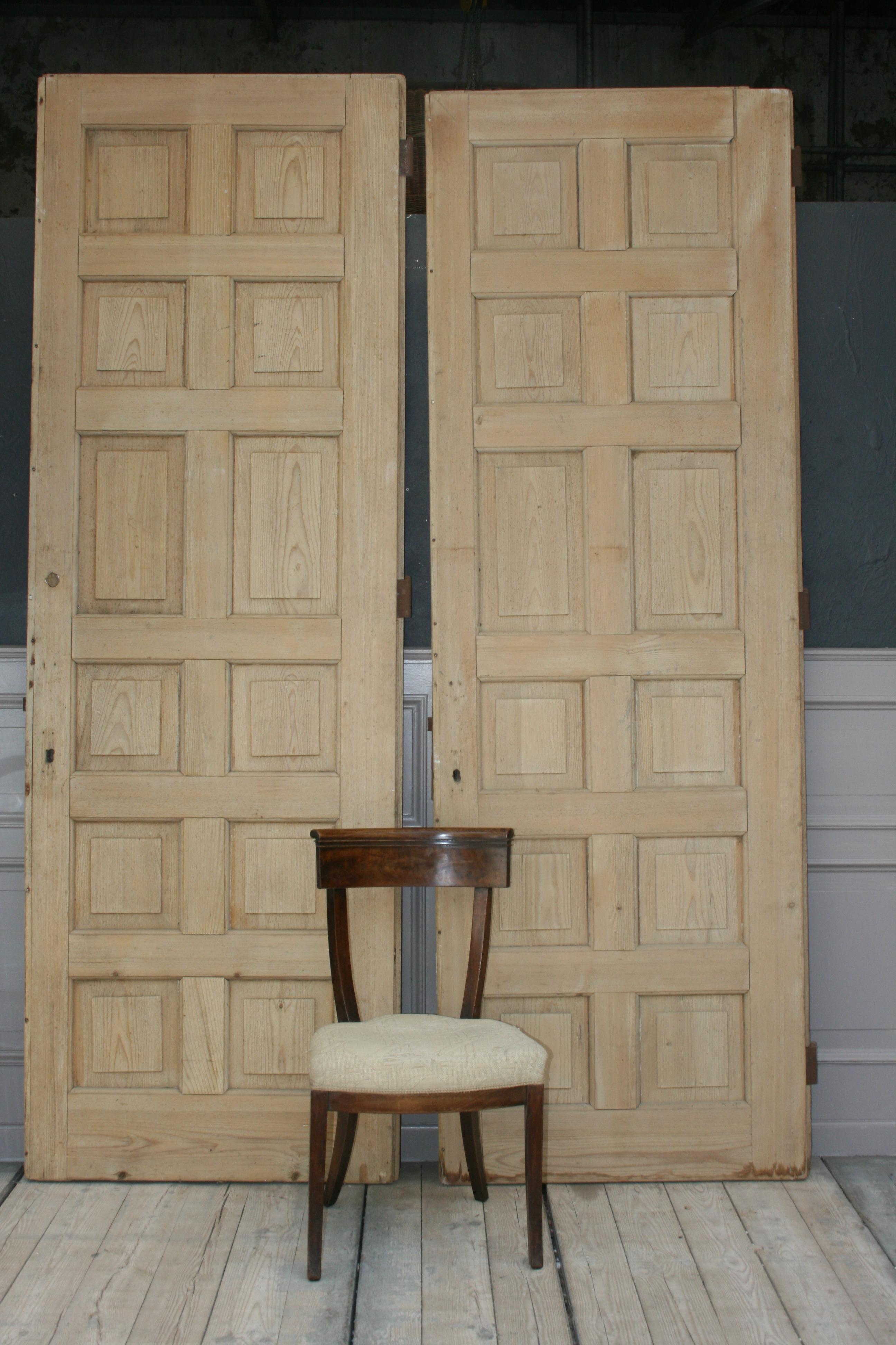 A pair of large antique single apartment doors from an Art Nouveau villa in Zurich (Switzerland) made of leached softwood. Both doors each have 12 cassettes, one of which is made of oak wood and can be opened with a brass handle as a small window.