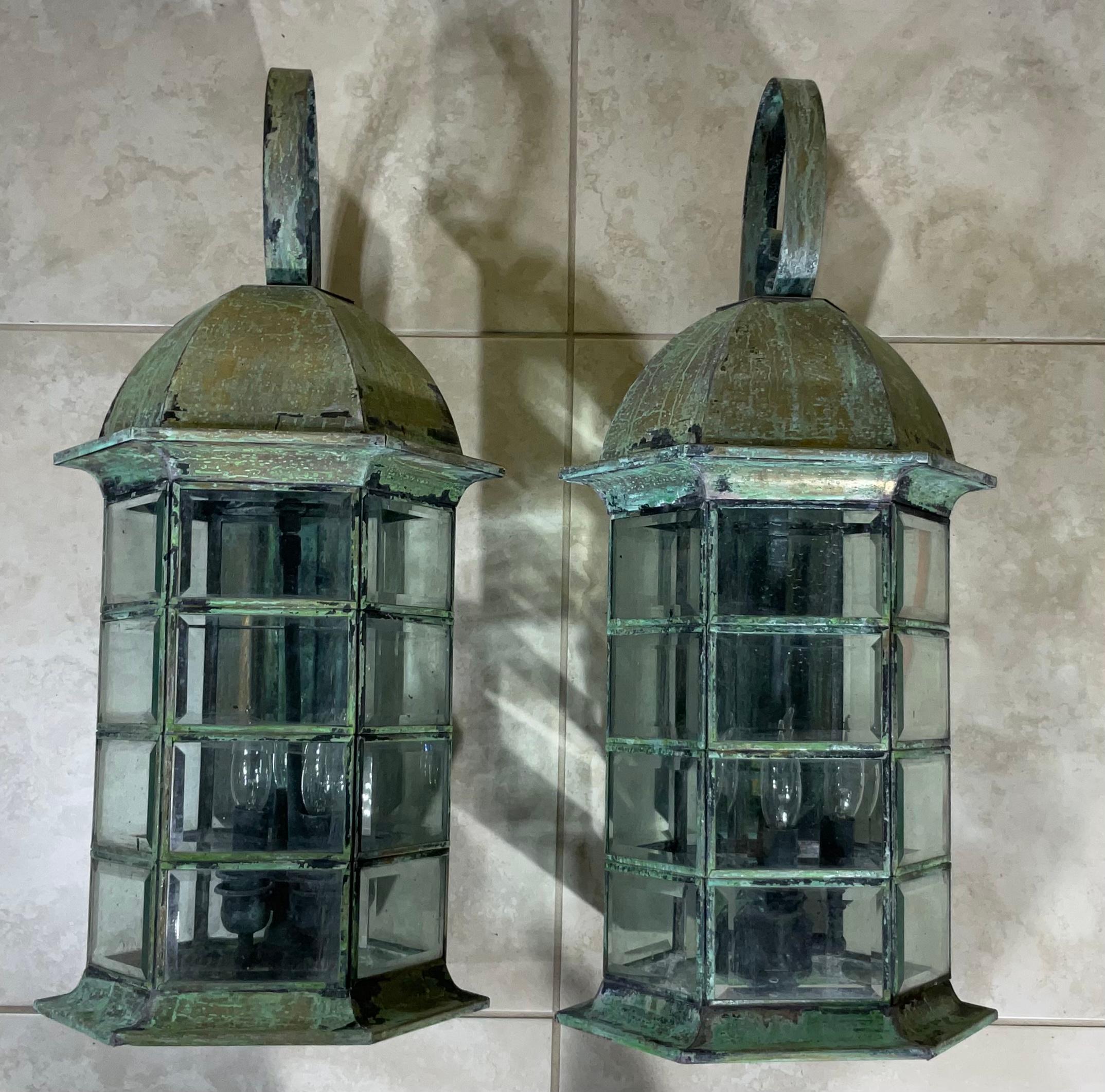 Pair of wall lantern or wall sconces, made of solid brass , beautiful patina, beveled glass , four 60/watt lights each lantern,
Suitable for wet locations, 
Great looking wall lanterns for any entrance.
