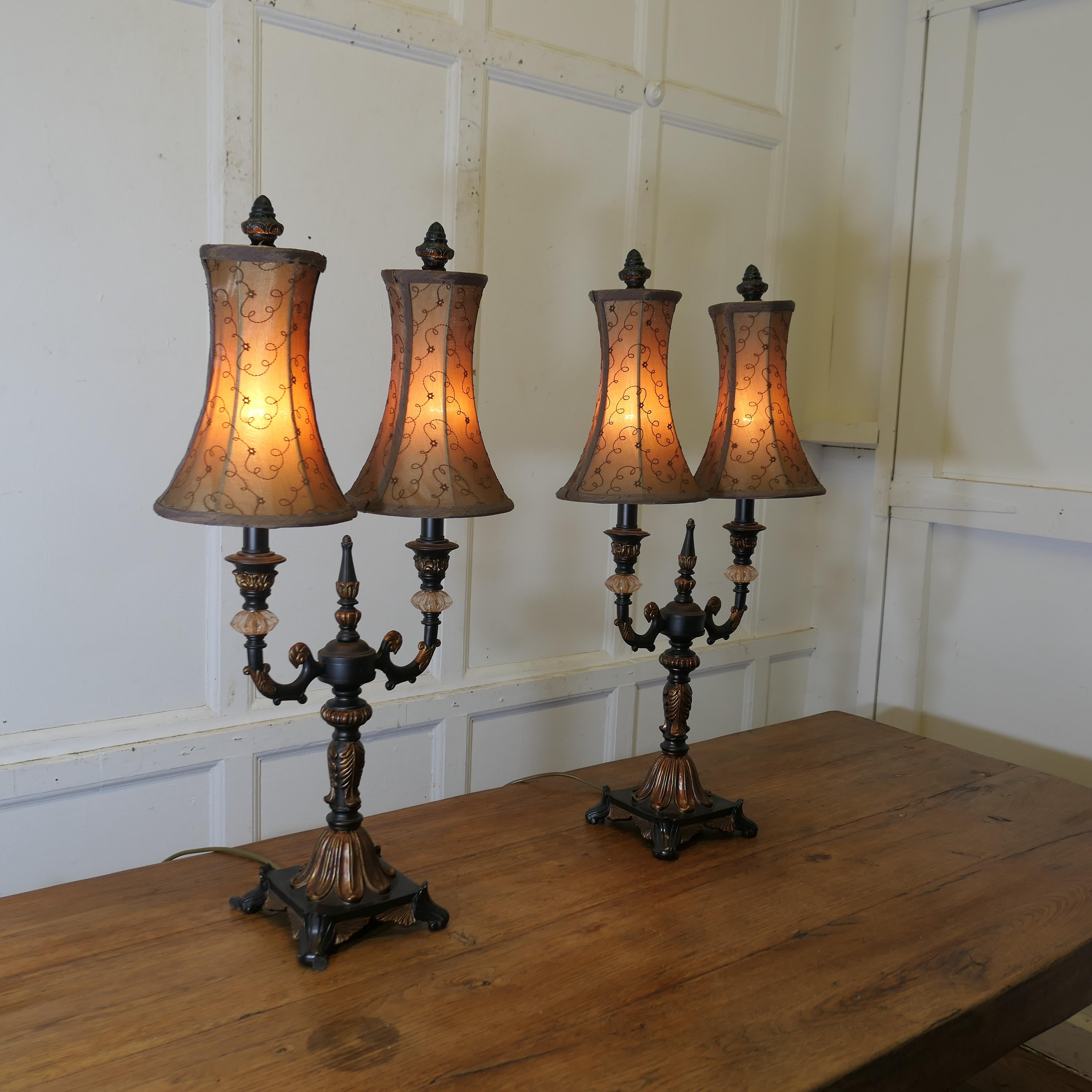Pair of Large Art Deco Hollywood Regency Twin Table Lamps

These are grand looking pieces, the lamps are black with coper gilding and jewelled decoration, they each have 2 large branches topped with a tall hand made lampshade
All in good working