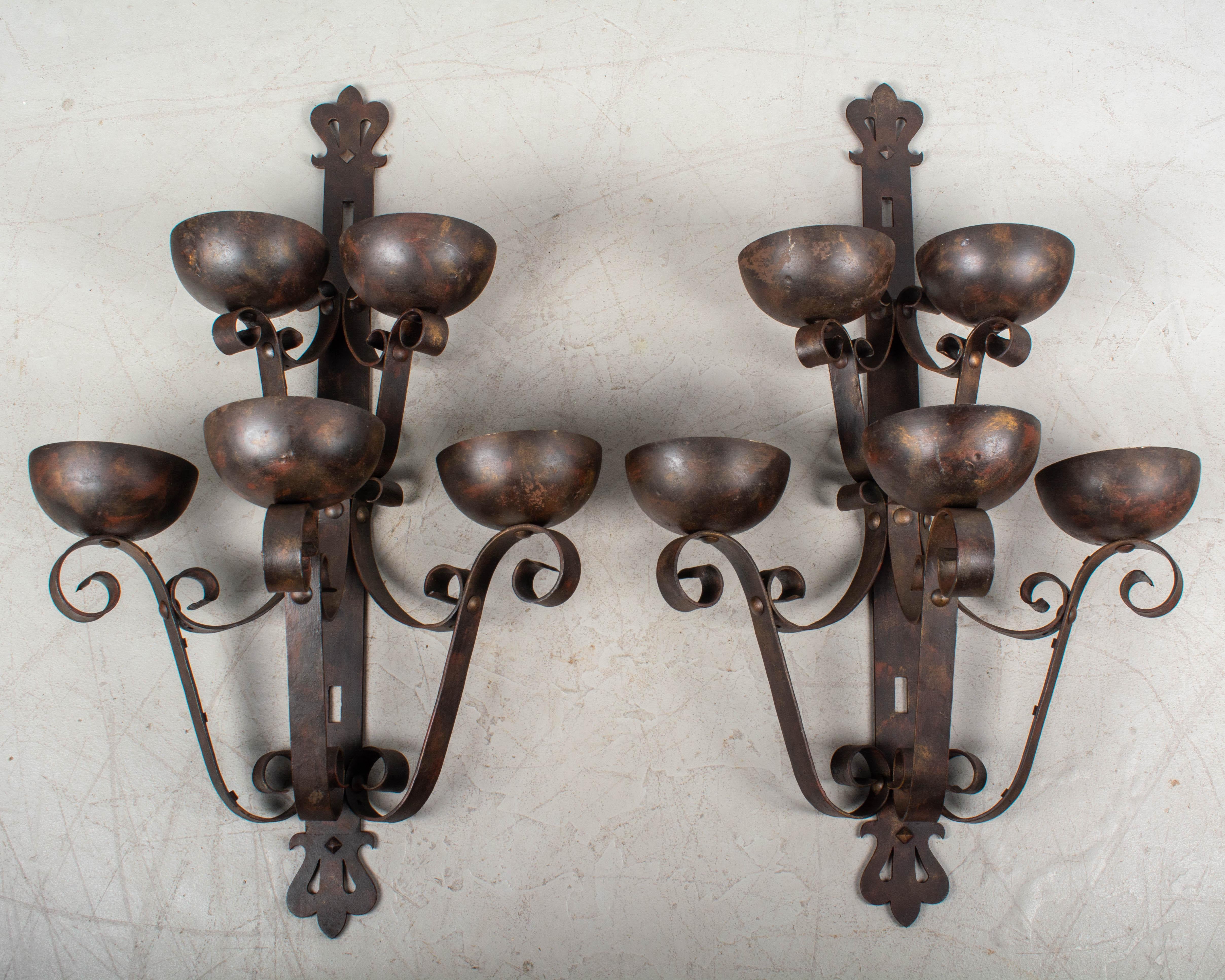 A pair of large Art Deco Spanish Revival style wrought iron architectural sconces with cold-painted finish made to look like bronze. Five half-dome torchiere up-lights create a dramatic effect when lit. Each dome is 7