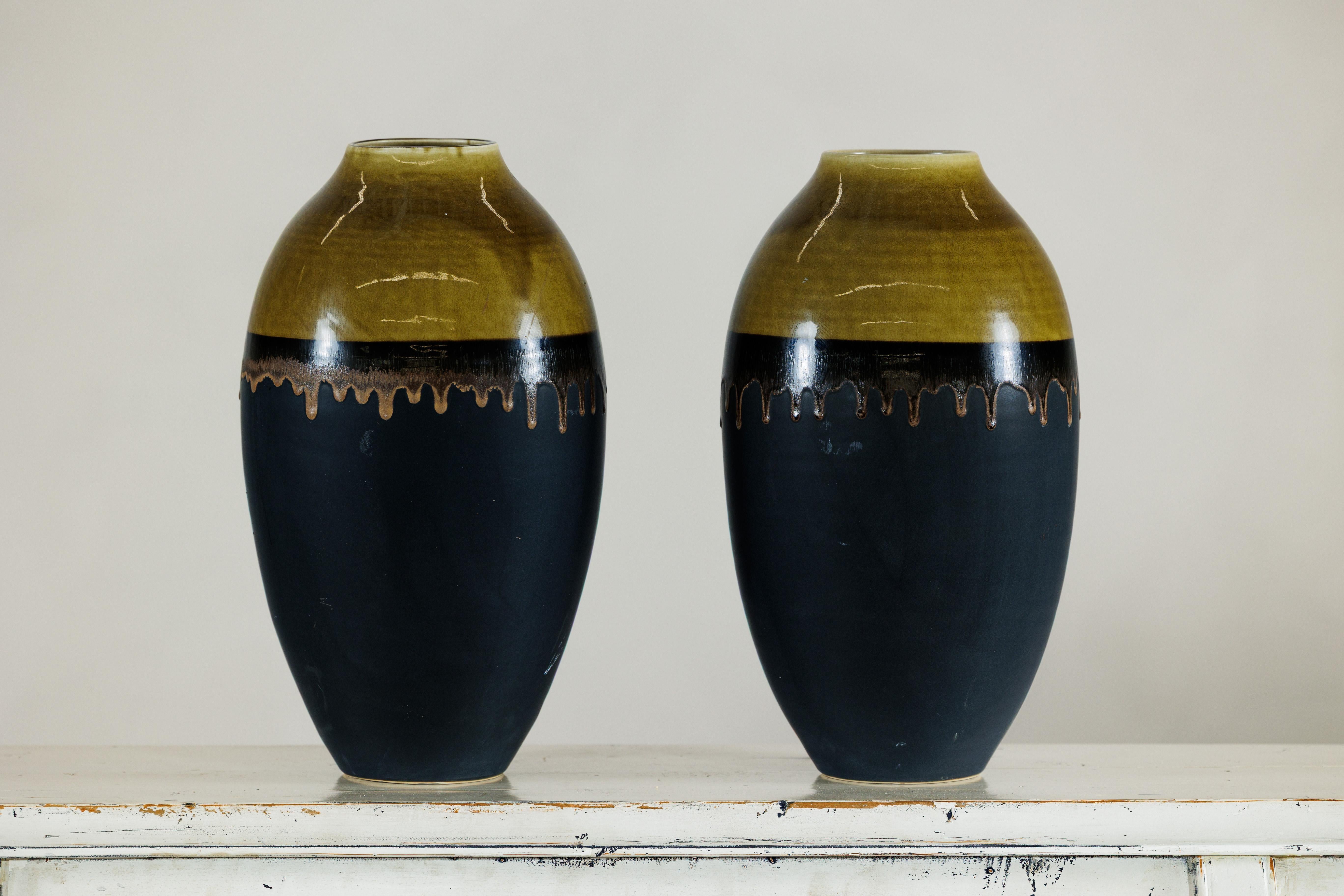 Cette paire de grands vases en céramique artisanale allie une présence sculpturale à des détails fabriqués à la main. Chaque vase mesure 16 pouces de haut, avec une forme arrondie et une large ouverture de 4 pouces. Ils conviennent donc parfaitement