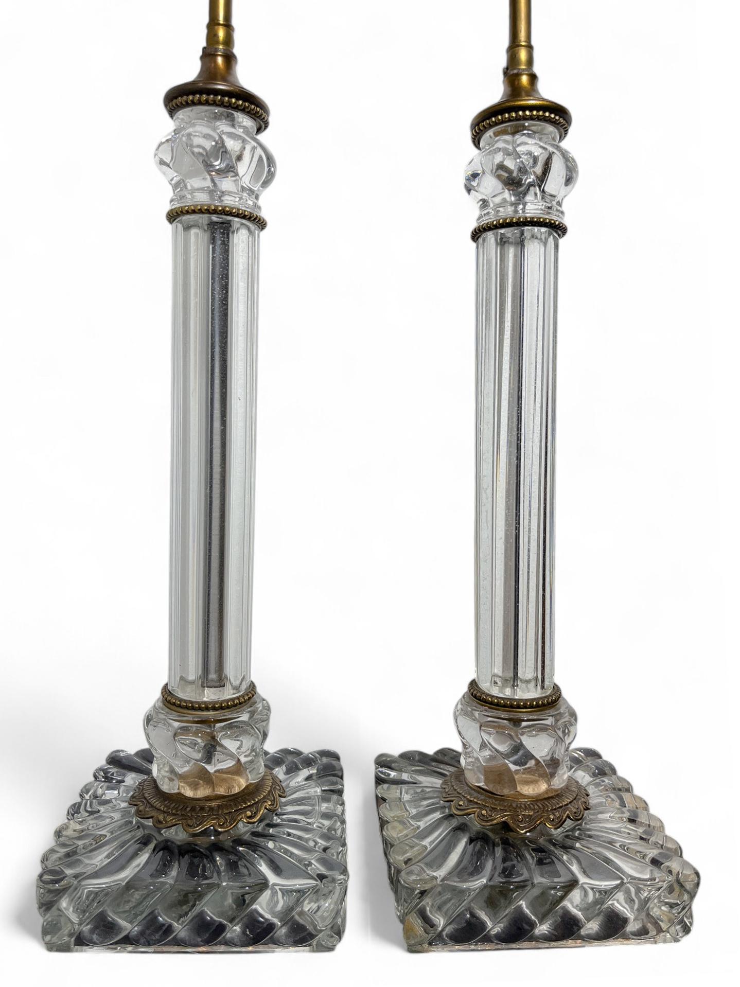Une impressionnante paire de lampes en cristal, fabriquées avec expertise par la société Baccarat, de renommée mondiale. Reposant sur des bases carrées, la paire est convexe, cannelée et torsadée au niveau des bases carrées et des sommets en