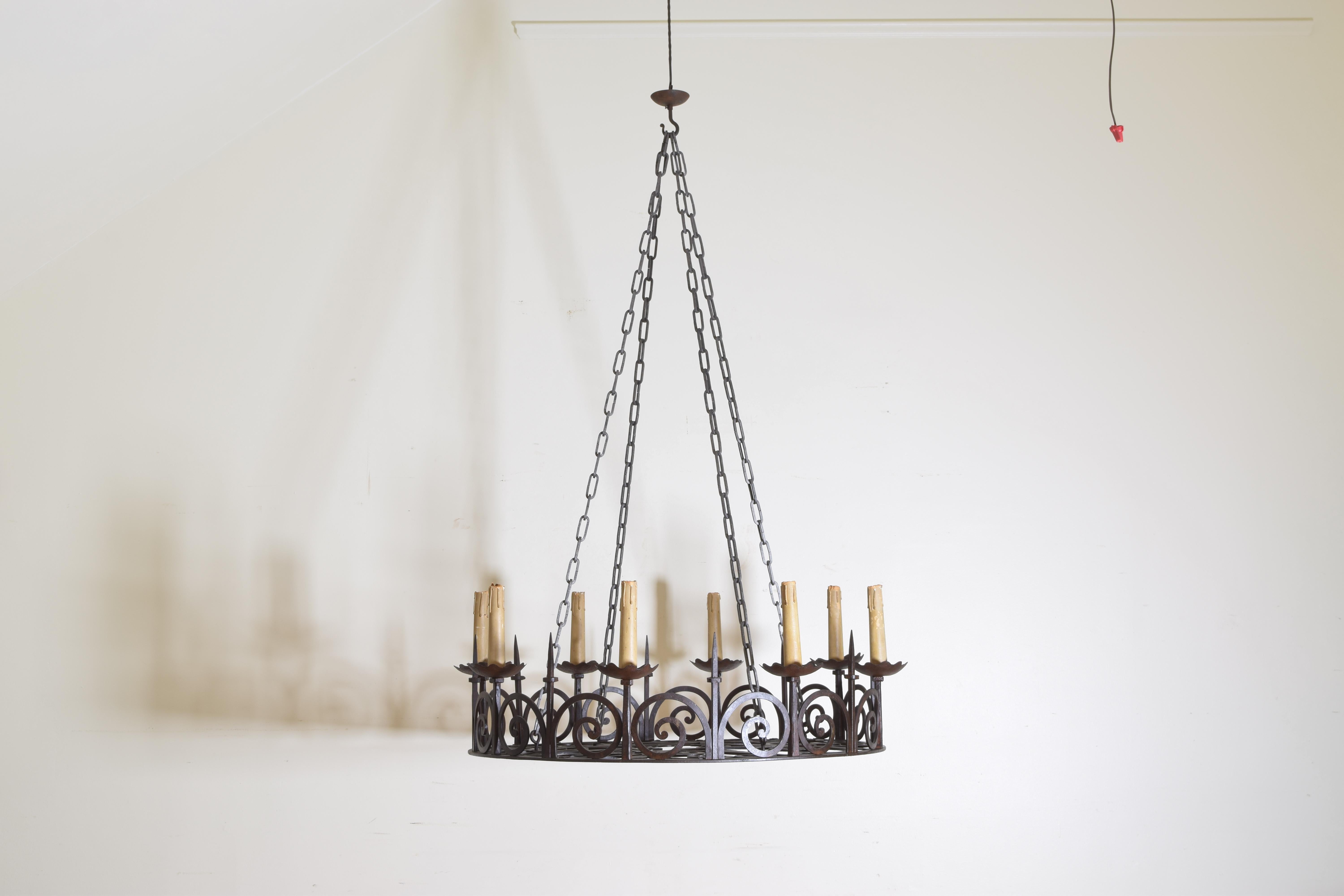 Suspended from four chains, these large banded chandeliers have elaborate hand wrought scrollwork in both the sides and bottoms, having large bobeches in turn with picket decorations.