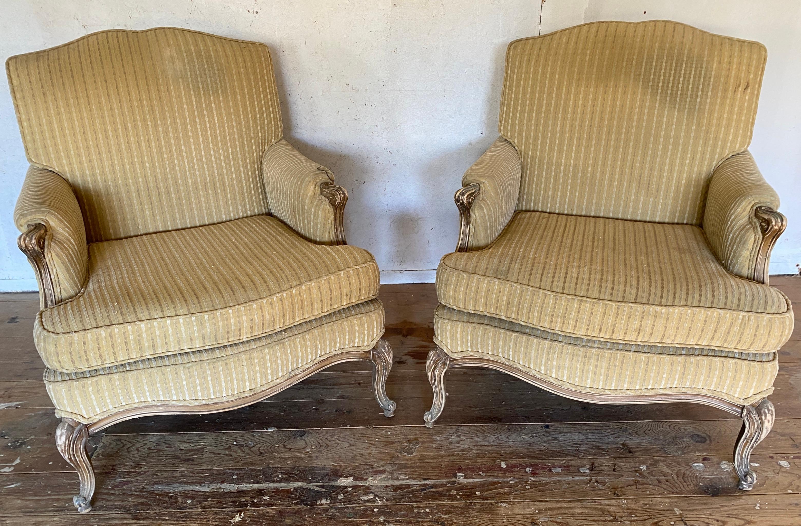 Pair of very comfortable and inviting Louis XV French Provincial style upholstered bergere club lounge chairs with cabriole legs. Upholstery needs refreshing but great pair of frames with generous proportions and comfortable seating. 
23