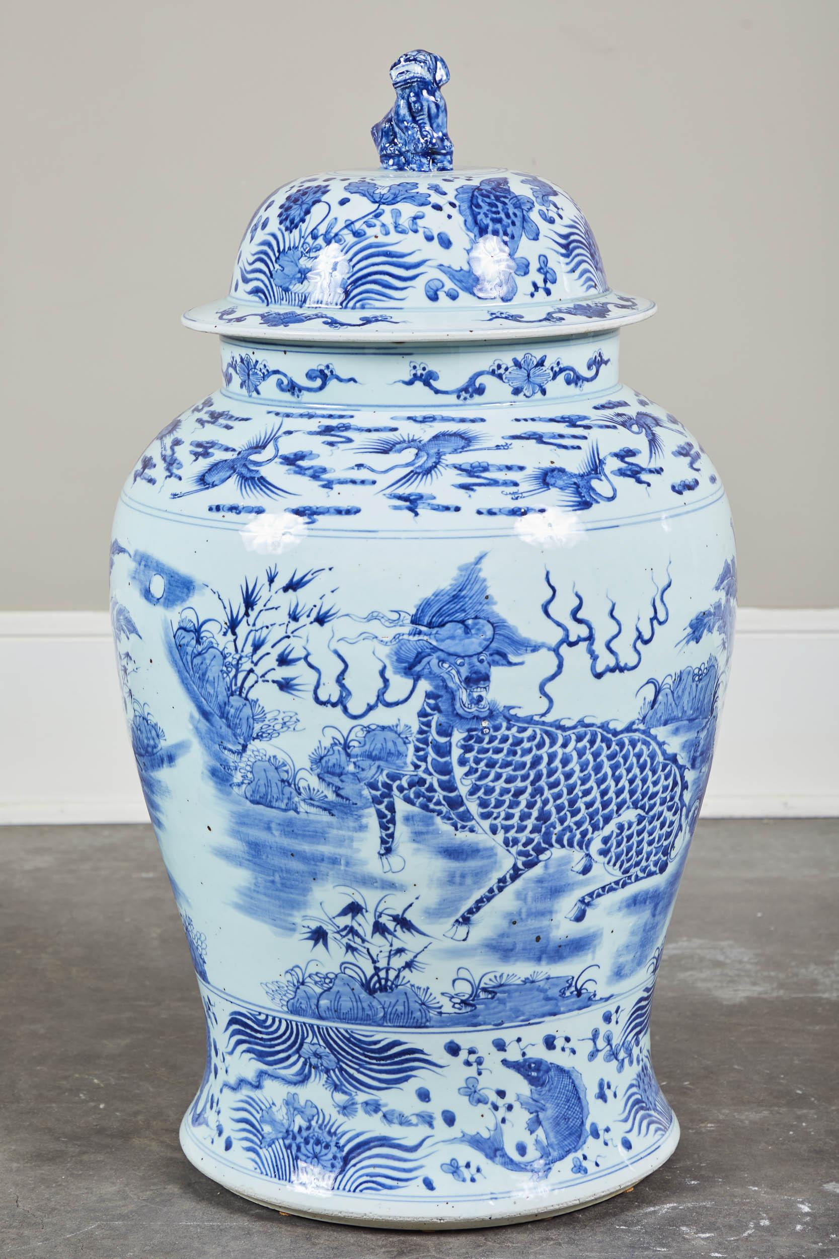 A pair of 20th century large blue and white Chinese ginger jars with lids. Foo dog handles top this pair of landscape and foliage detailed vases.
