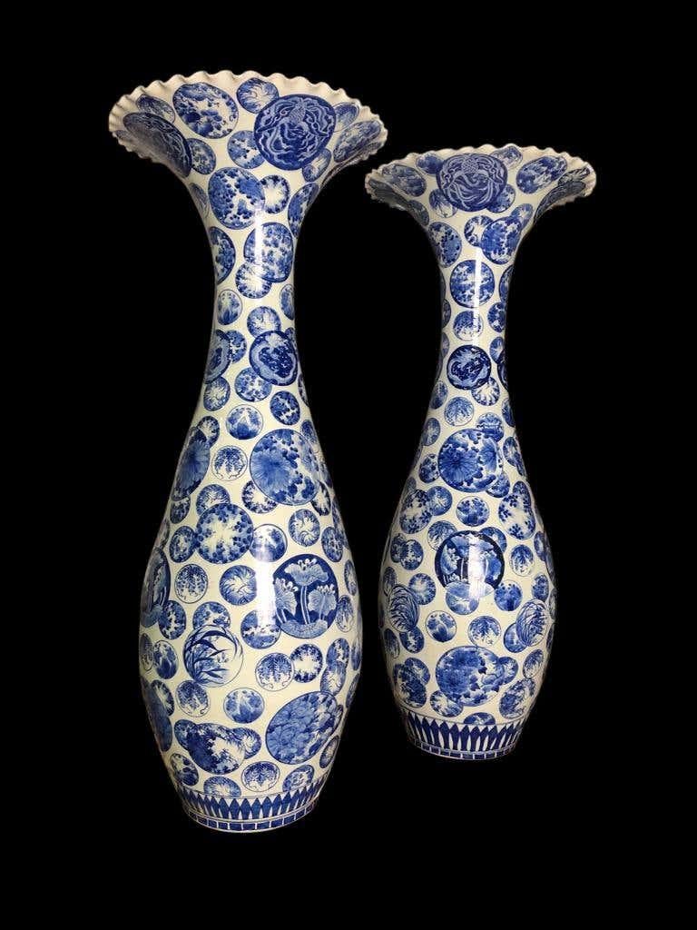 A beautiful pair of large blue and white Porcelain Japanese decorative vases, 19th century. Absolutely stunning in person, standing at almost 4 feet tall. The pair are decorated in Japanese style, with visuals of flowers, shrubs and a Japanese