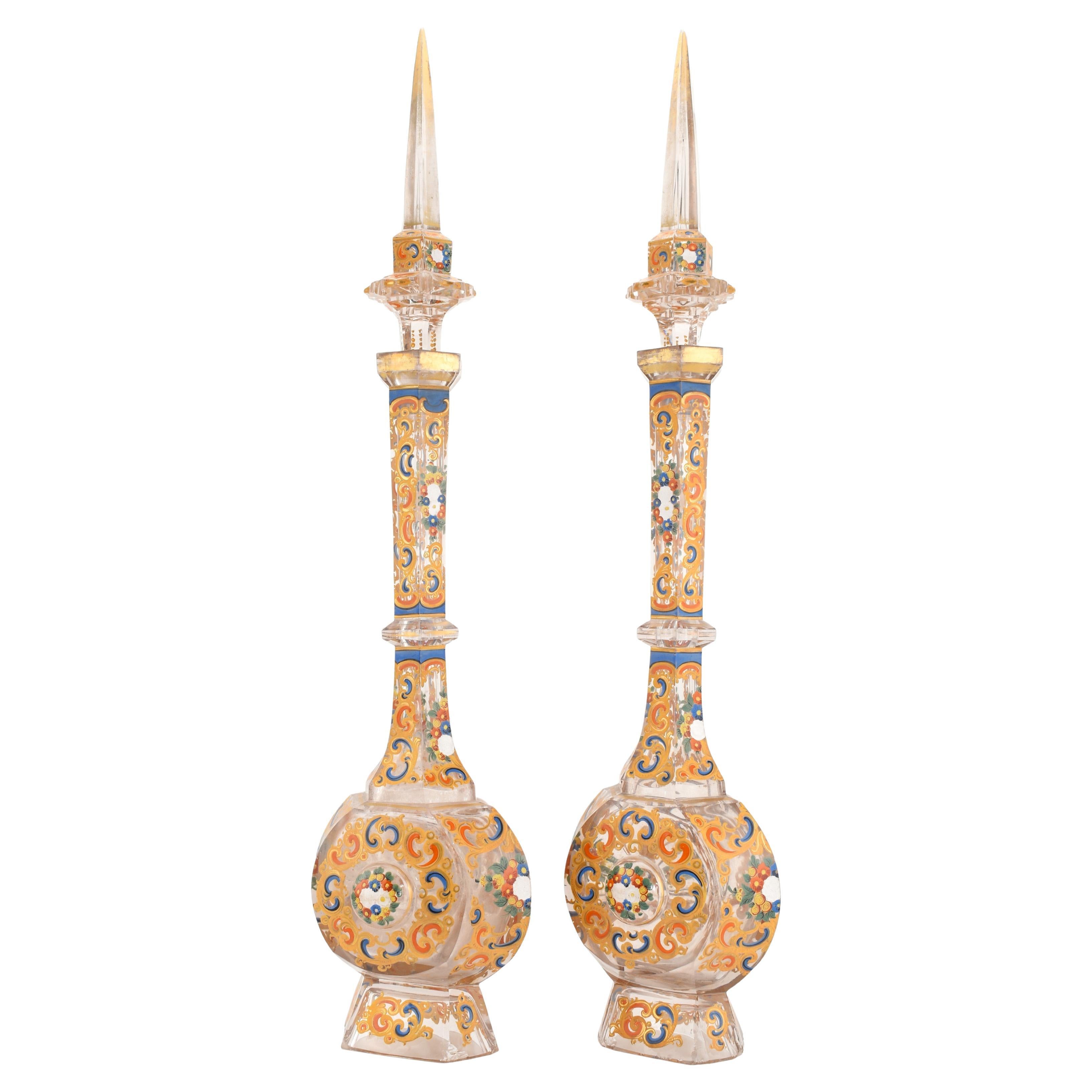 Magnifique paire de carafes à bouchon en verre clair émaillé et taillé de Bohème du milieu du XIXe siècle, mettant en valeur l'art et l'artisanat de l'époque. Chaque carafe présente un corps aplati et un col à facettes, complétés par un élégant