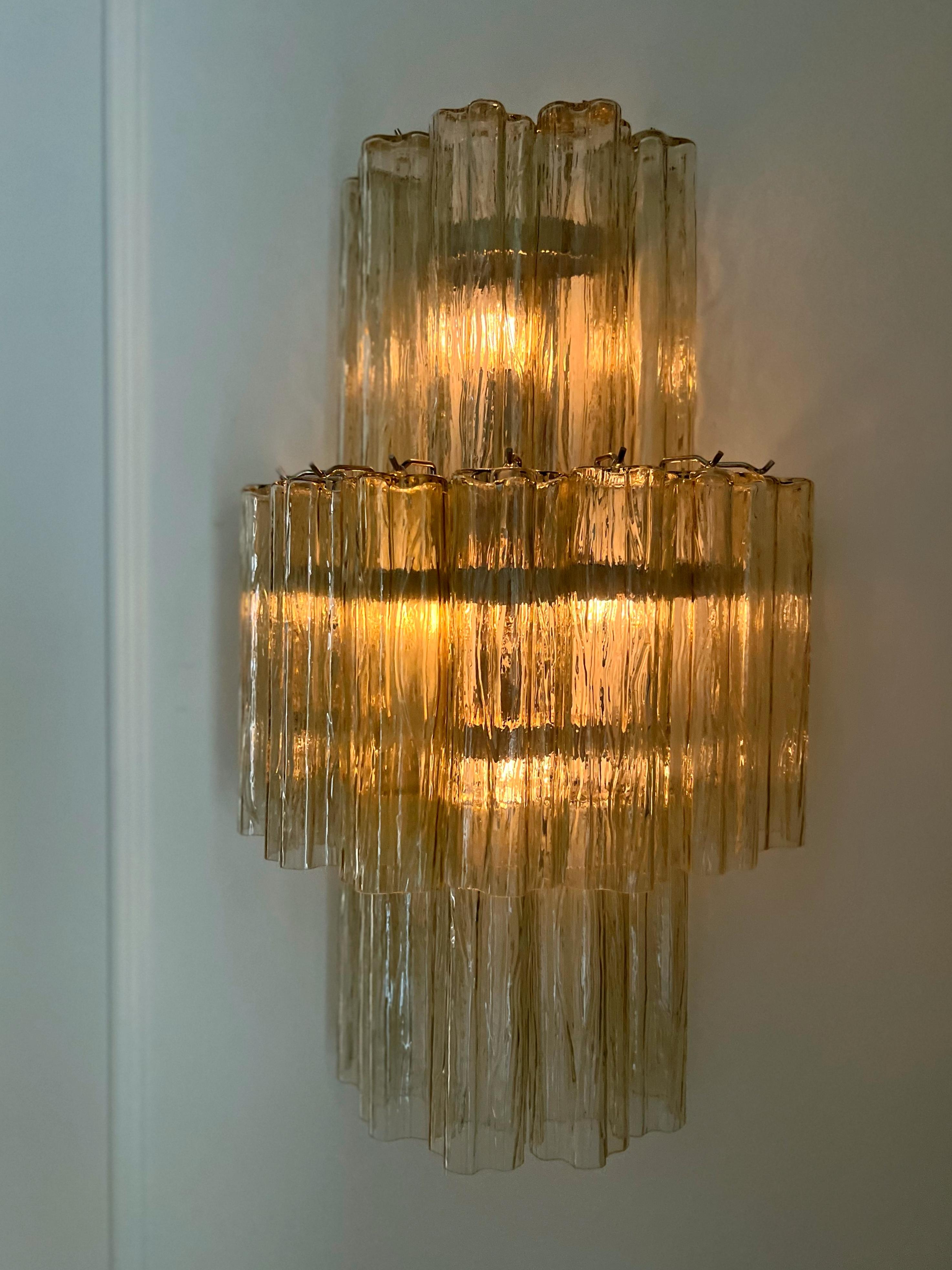 Paire de grandes appliques Murano en verre de couleur miel, composées de dix-huit prismes tubulaires avec finitions et raccords en chrome. Verre du district italien de Murano. 
Style traditionnel italien du milieu du siècle, produit en Italie au