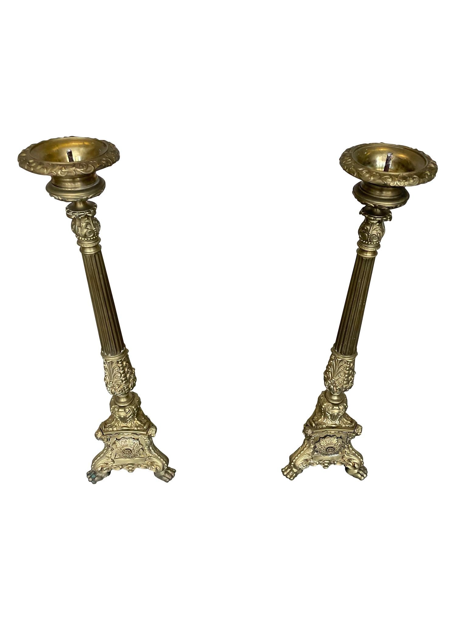 Lovely pair of large brass Altar Candlesticks. Adorned with classical embellishments, a pair of winged cherubs at the base, and on paw feet. Perfect for an added touch of drama and elegance to any living space. Fully functional. 

Dimensions:
10