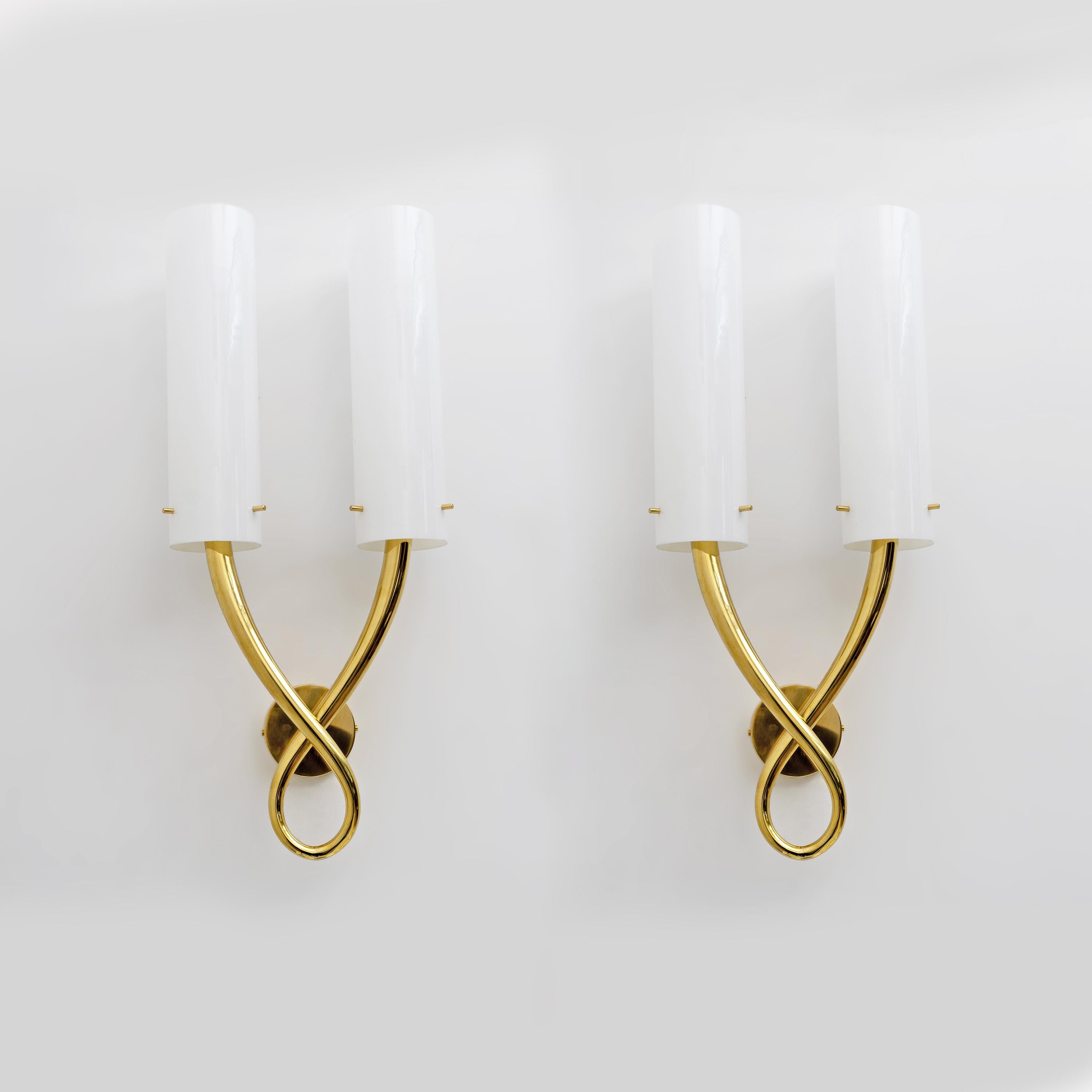 Pair of Gio Ponti style wall lamps. The body of the chandelier features two cylindrical white Murano Incamiciato glass lampshades, arranged symmetrically, the cylinders measure 38 cm in height. Each lampshade is supported by a curved structure in