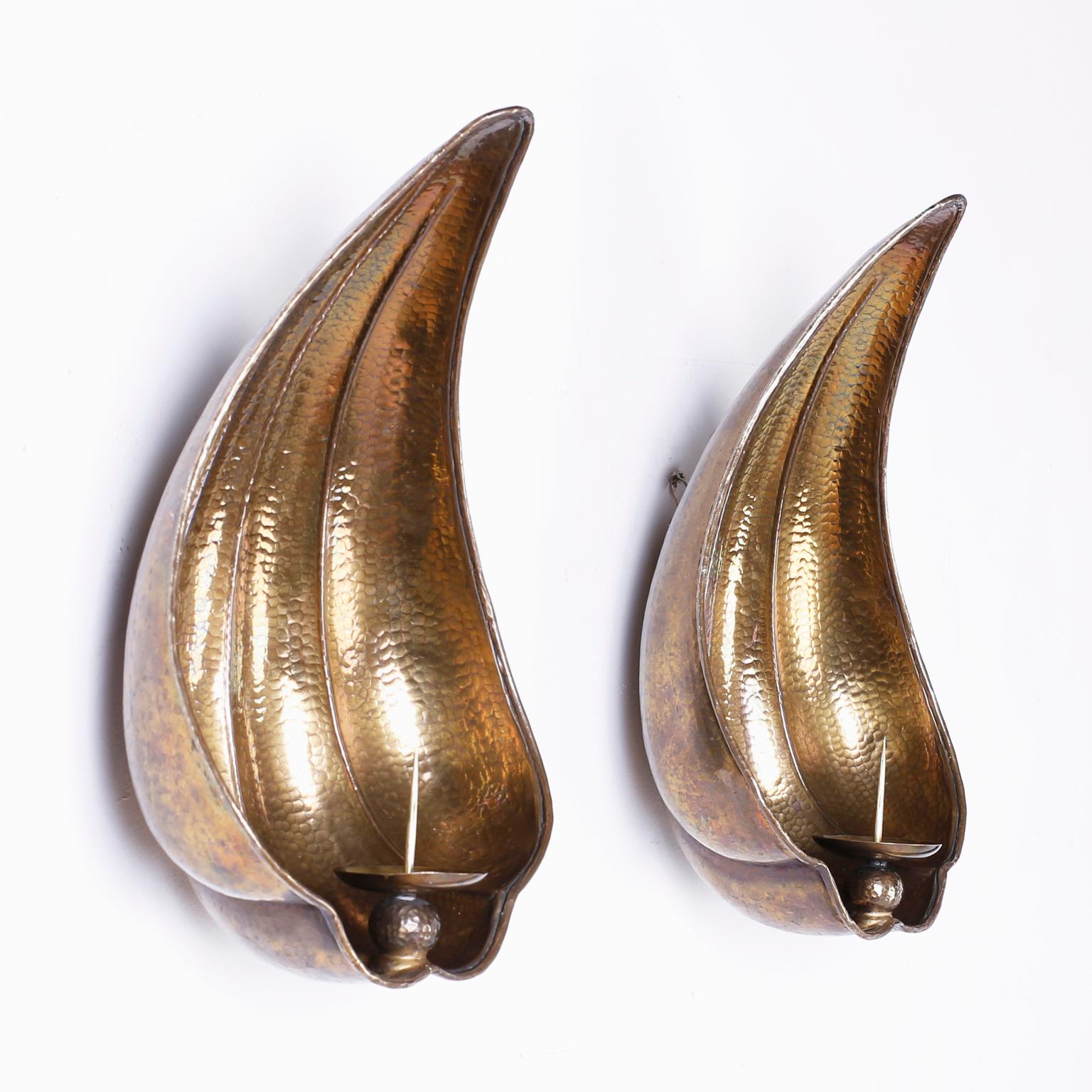 Brass concave sea shell inspired candle powered sconces with a hip stylized form and a chic burnished finish.
 
