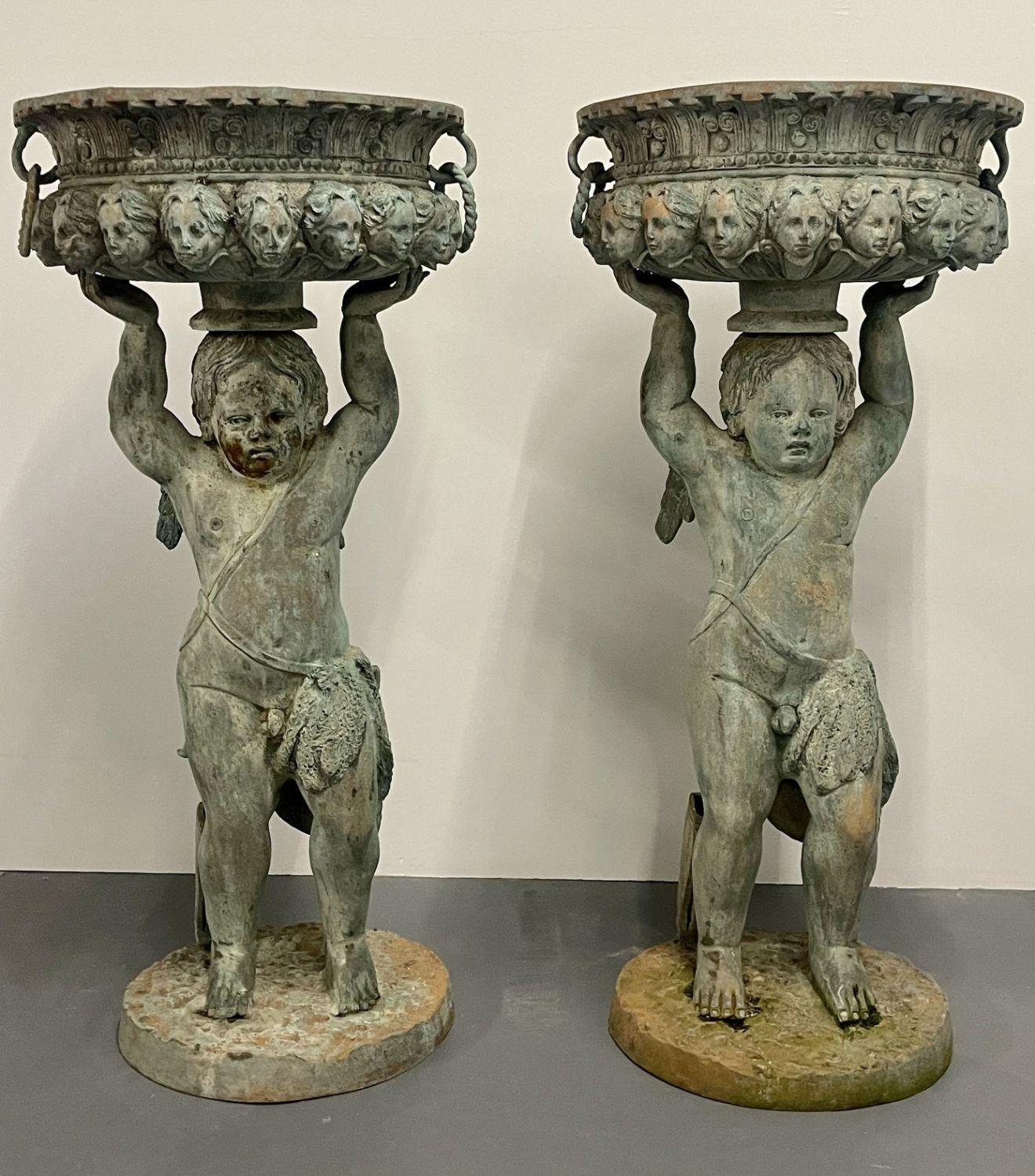 Pair of large bronze Cherub planters, Roman, Greek Neoclassical. A finely case pair of planters each having an basket with handles having faces around the apron supported by a bare breasted cherub holding up the pot. The pair nicely