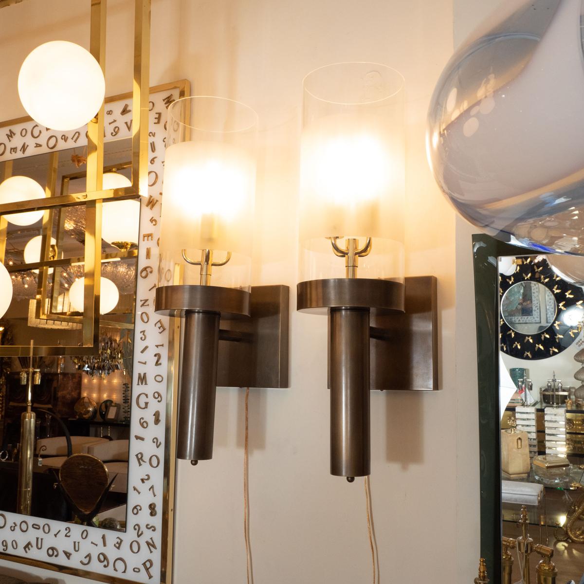 Pair of large bronze single arm sconces with clear and frosted Lucite shades.