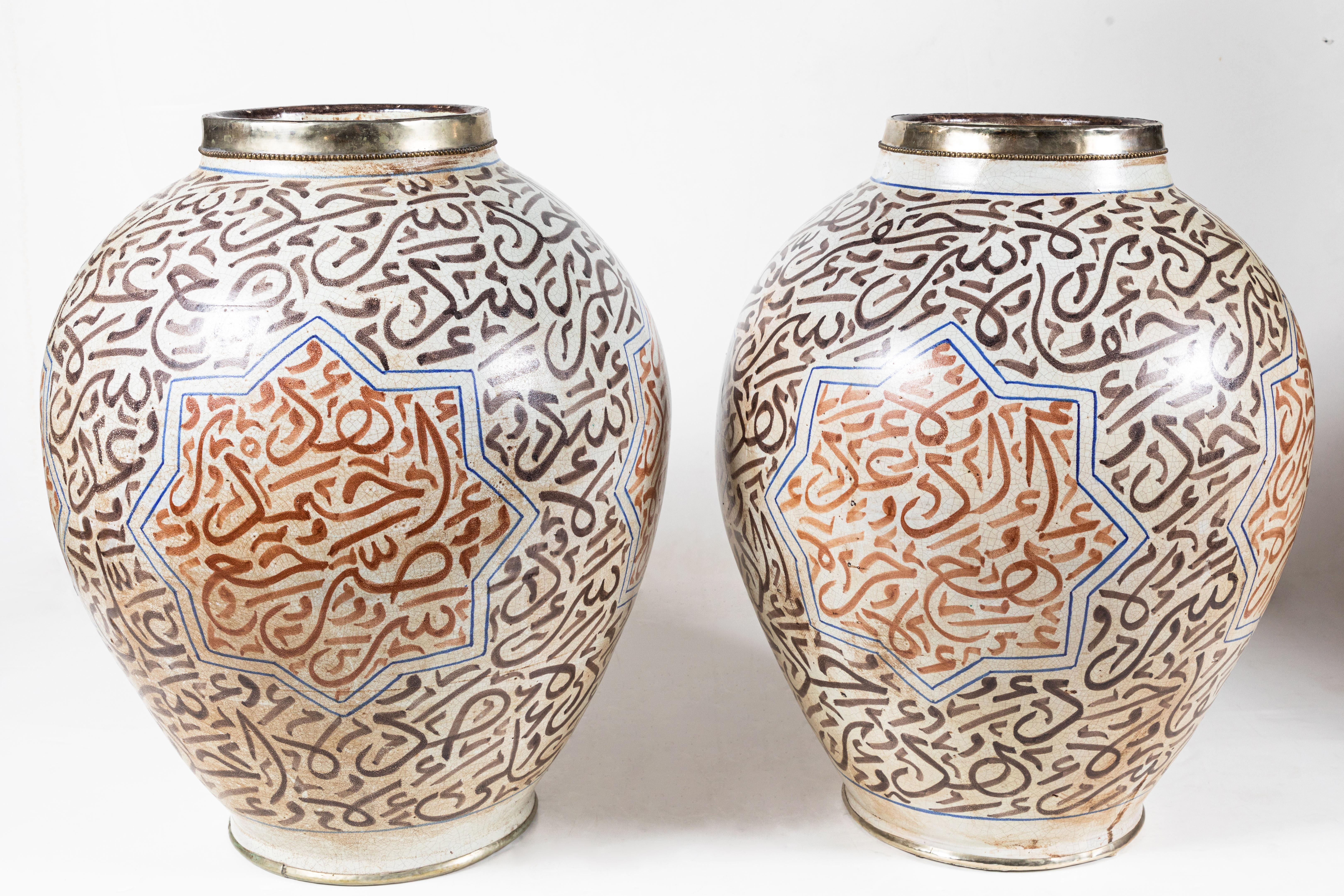 Stunning pair of rare, hand-thrown, hand painted, turn-of-the-century, lidded urns trimmed in silver. Each covered in abstracted, Arabic writing and embellished with Moorish stars.