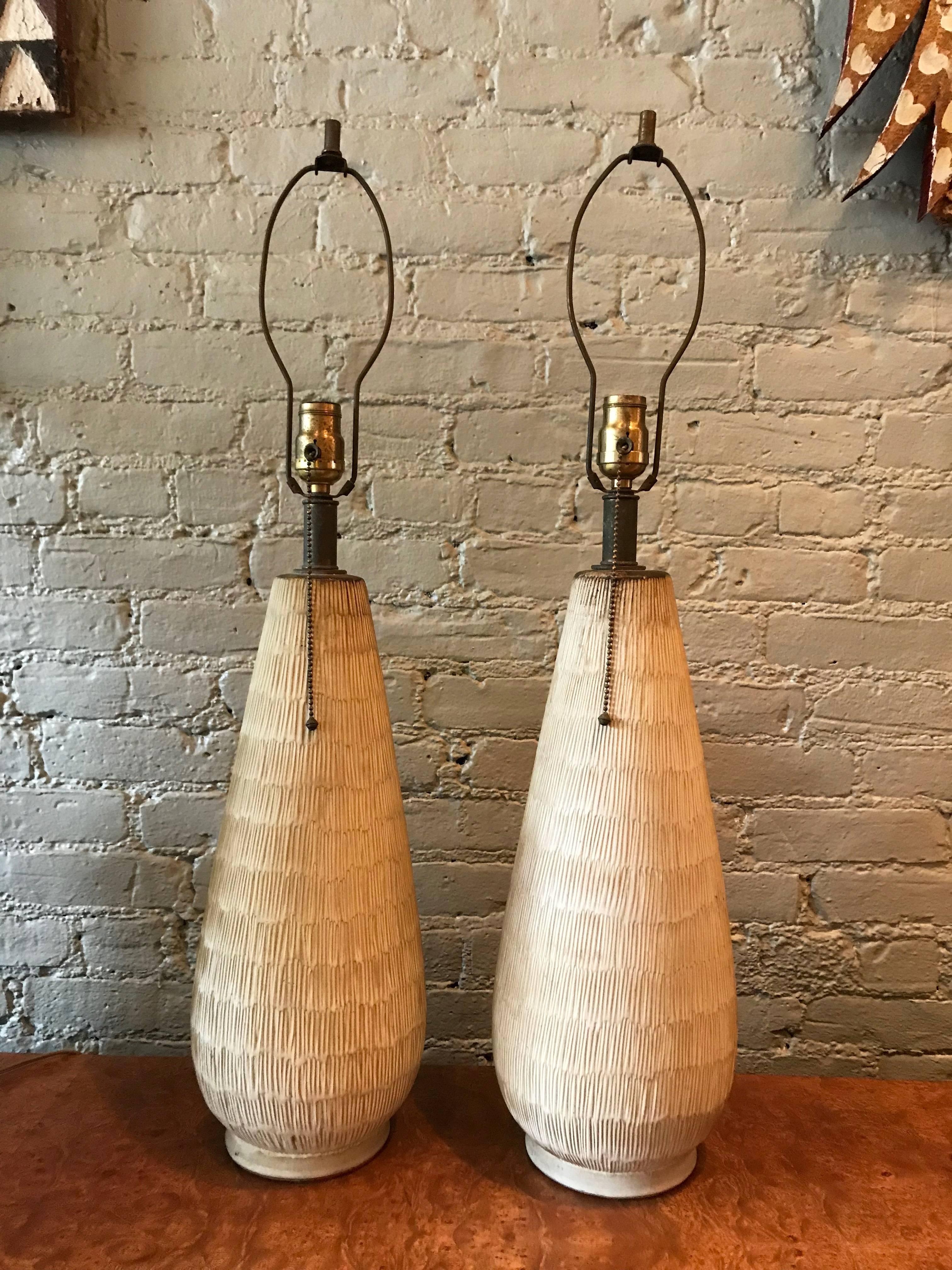 Pair of large Mid-Century Modern, studio, art pottery table lamps by Lee Rosen feature incised, earthenware ceramic bases with brass necks and pull chains. Height to the neck is 23 inches and overall height is 32 inches.