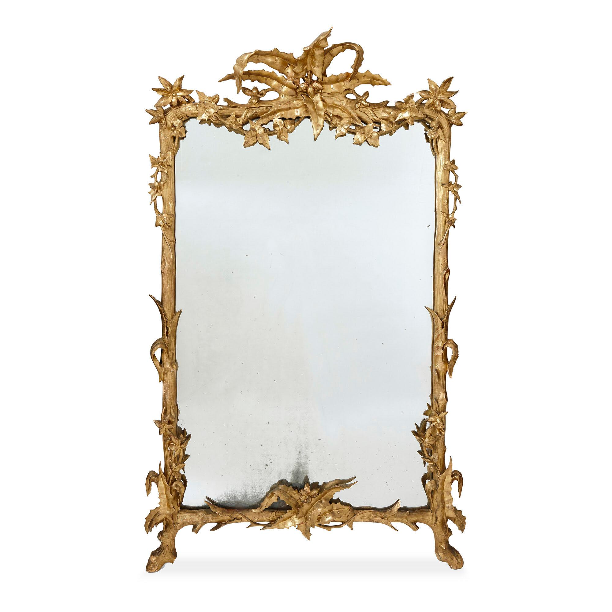 Pair of large carved and gilt wood floral mirrors
French, 19th century
Measures: Height 210cm, width 132cm, depth 30cm

Each mirror in this pair features a richly carved and warmly gilt wooden frame. The frame of each is carved in a striking