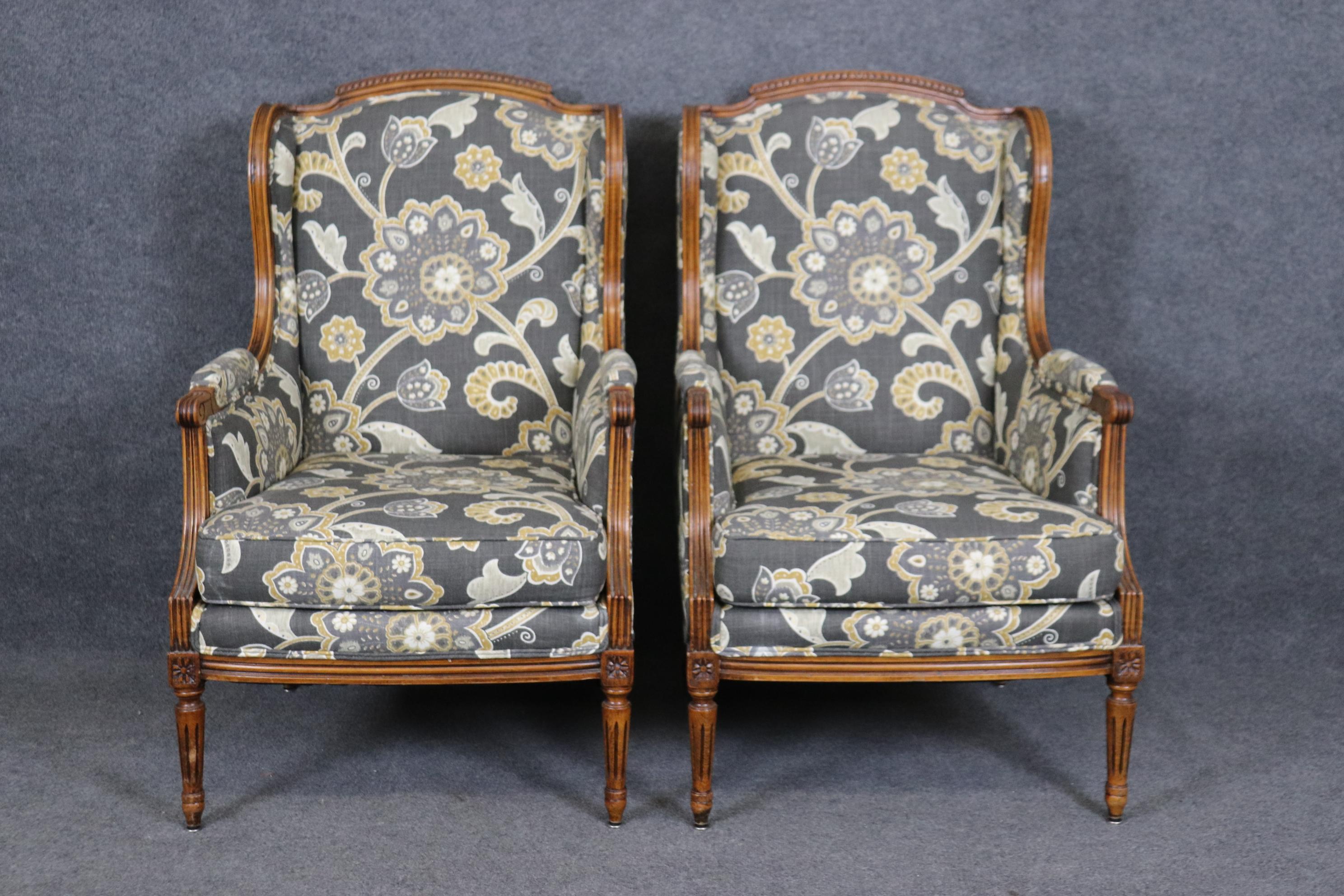 This is a beautifully upholstered pair of French carved walnut bergere chairs of large scale. The scale is tall and wide and the condition is rather good for a set of 1950s era pair of chairs.  Measures 43 tall x 26.25 wide x 32.25 deep and seat