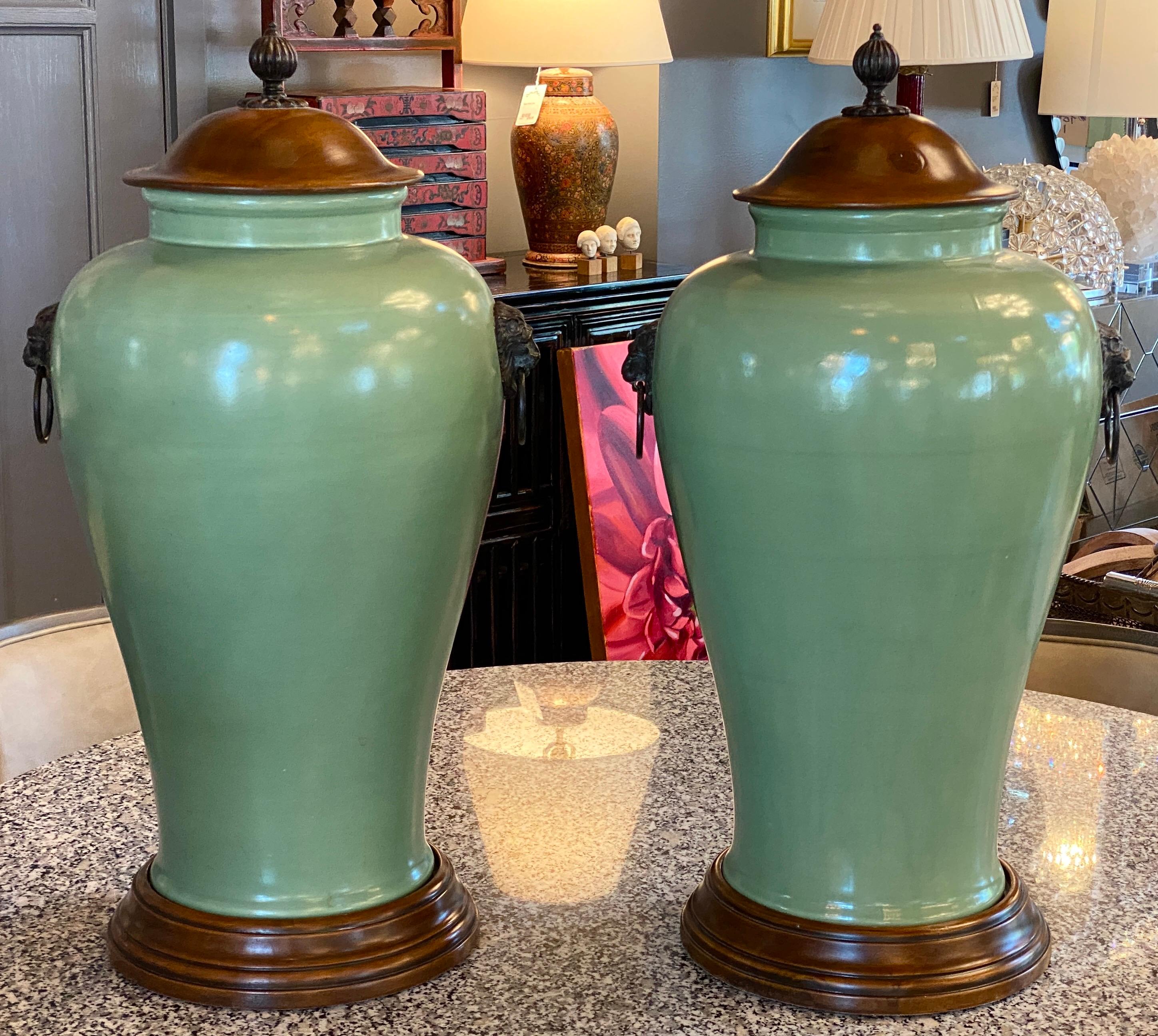 Pair of large Celadon pottery Urns with wooden lids and metal lion handles.