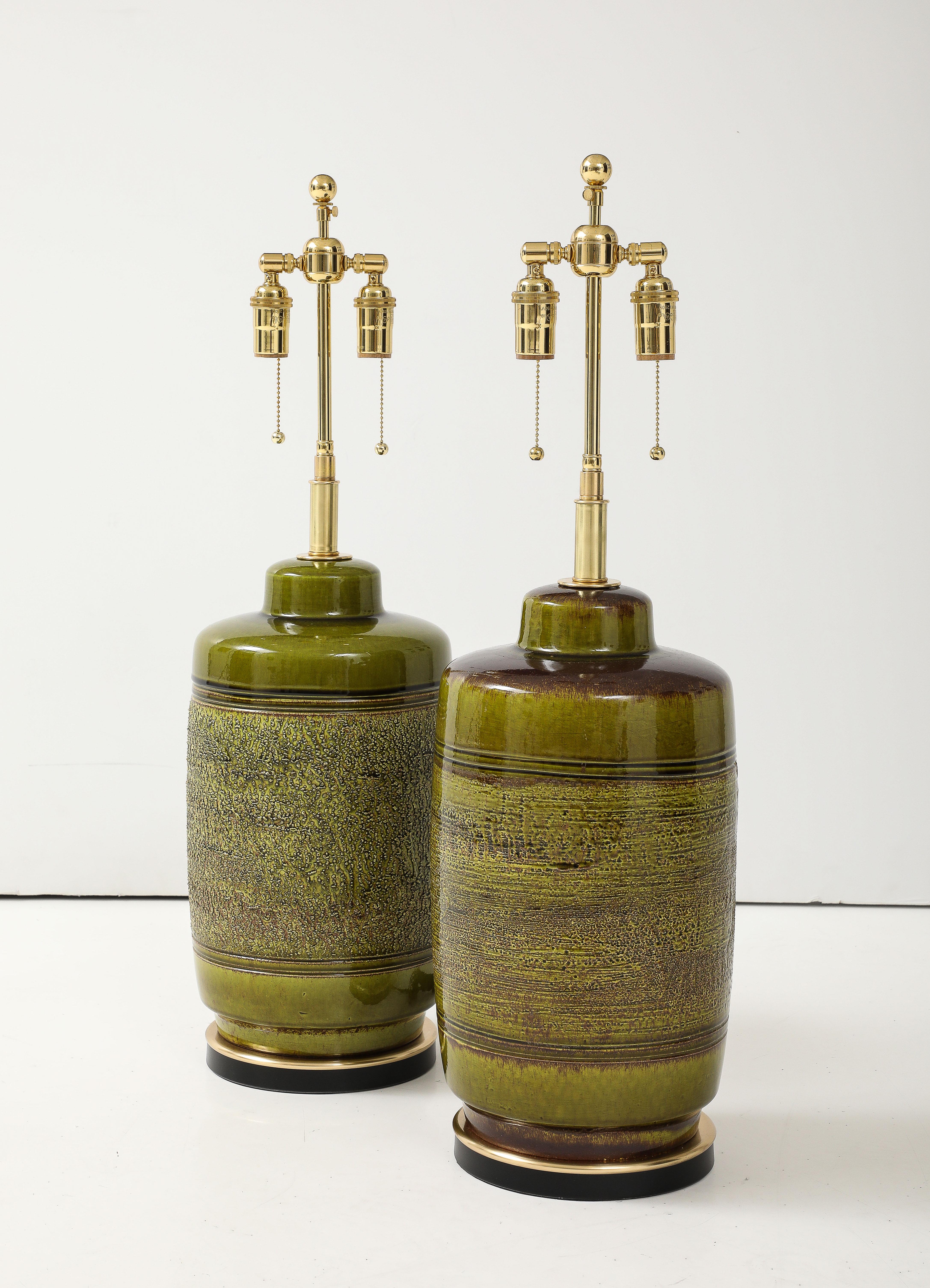 Paire de grandes lampes en céramique des années 1960 avec une finition en glaçure texturée de style brutaliste.
Les lampes en céramique en forme de tonneau reposent sur des socles noirs.  avec des garnitures en laiton et ils ont été nouvellement