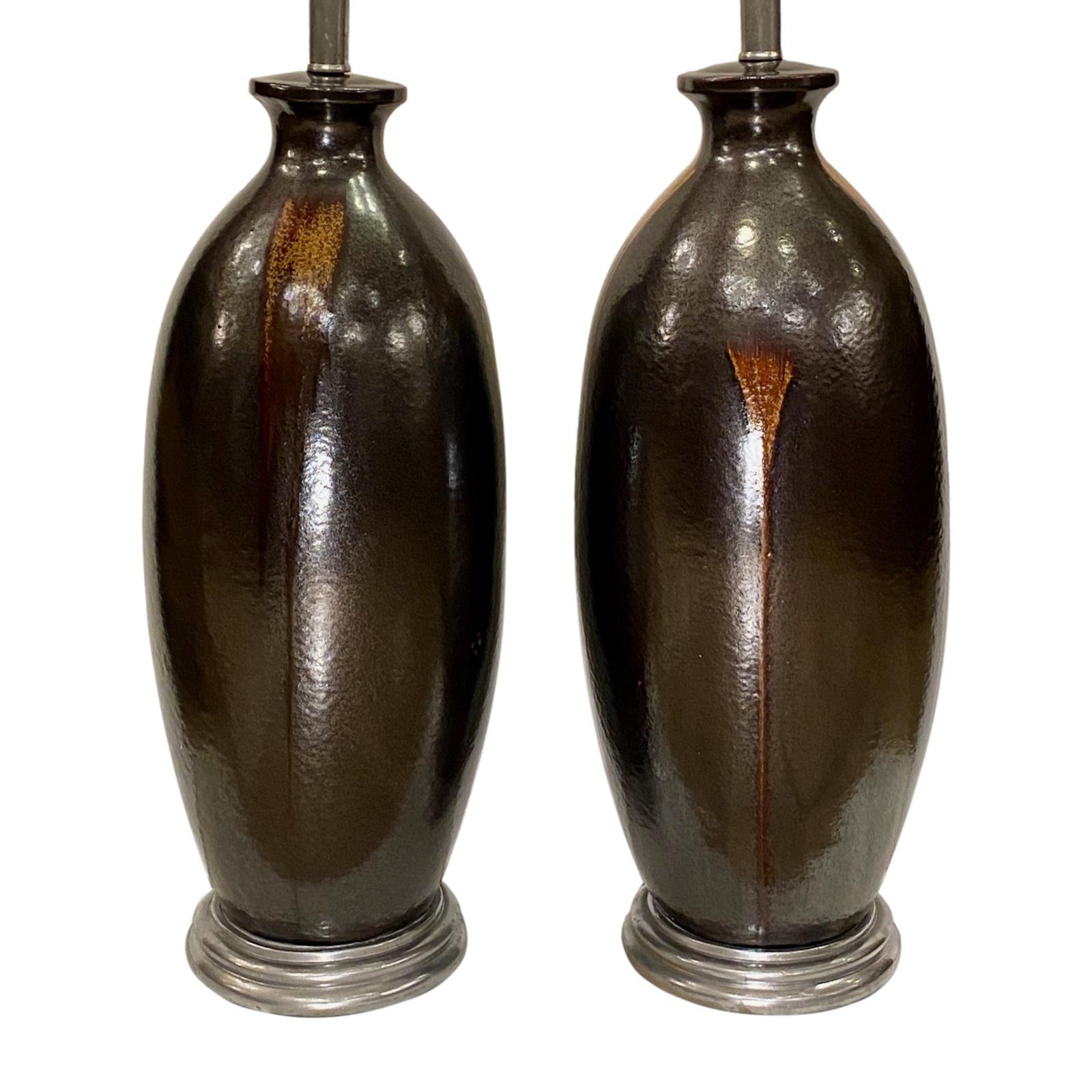 A pair of large circa 1950's French brown-glazed ceramic table lamps with silver leafed bases.

Measurements:
Height of body: 24