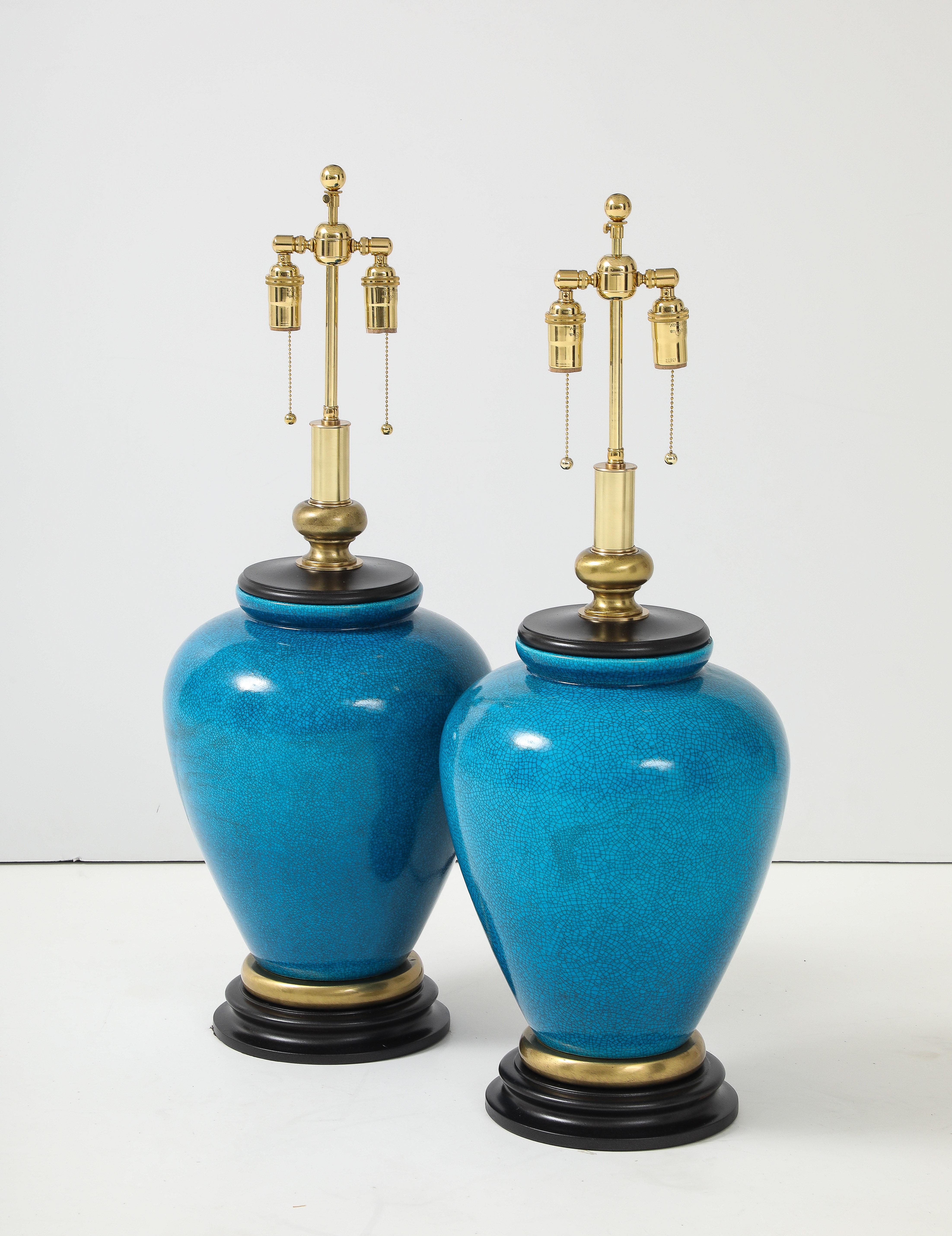 Wonderful pair of large ceramic lamps with a Beautiful Cerulean blue crackle glaze.
The lamps are mounted on turned wooden and brass bases and they have been Newly rewired 
with adjustable polished brass double clusters and silk rayon cords.
The
