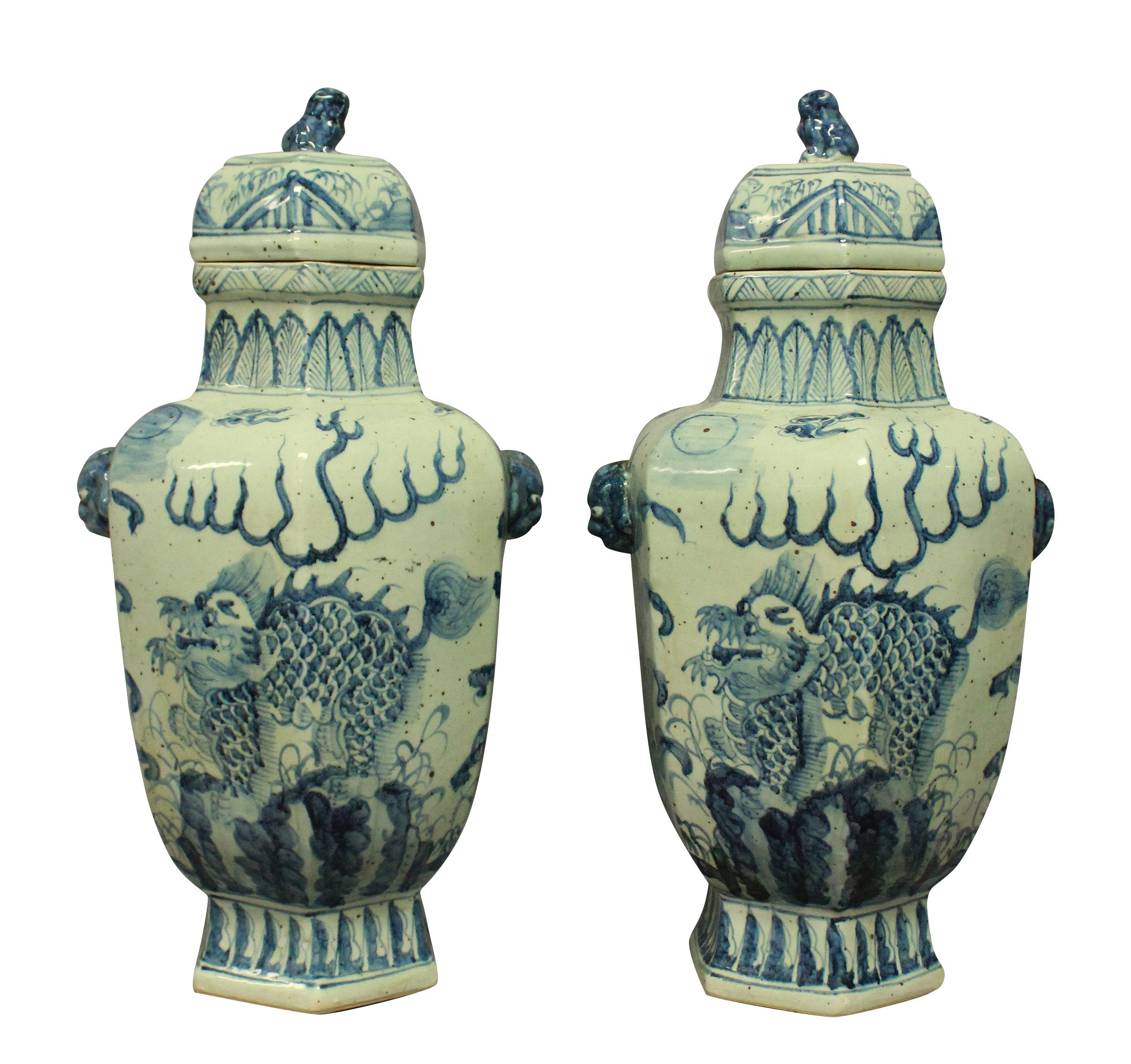 A pair of large hand painted blue and white Chinese vases with covers. Of bulbous hexagonal form, each depicting dragons and the covers with dog of foo finials.