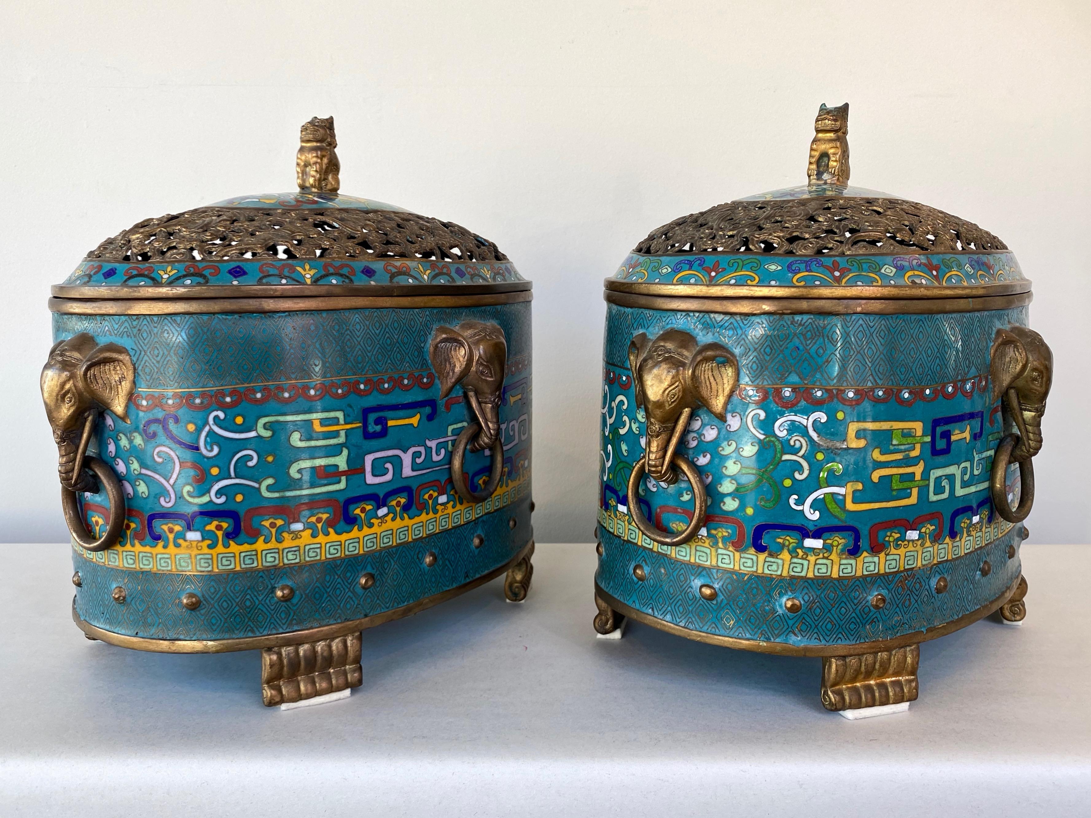 A pair of large and uncommon 1960s Chinese cloisonné & brass oval shaped censers with elephant head handles and foo dog-topped pierced lids.

Detailed, colorful, and well-executed cloisonné decoration with finely wrought brass line work and