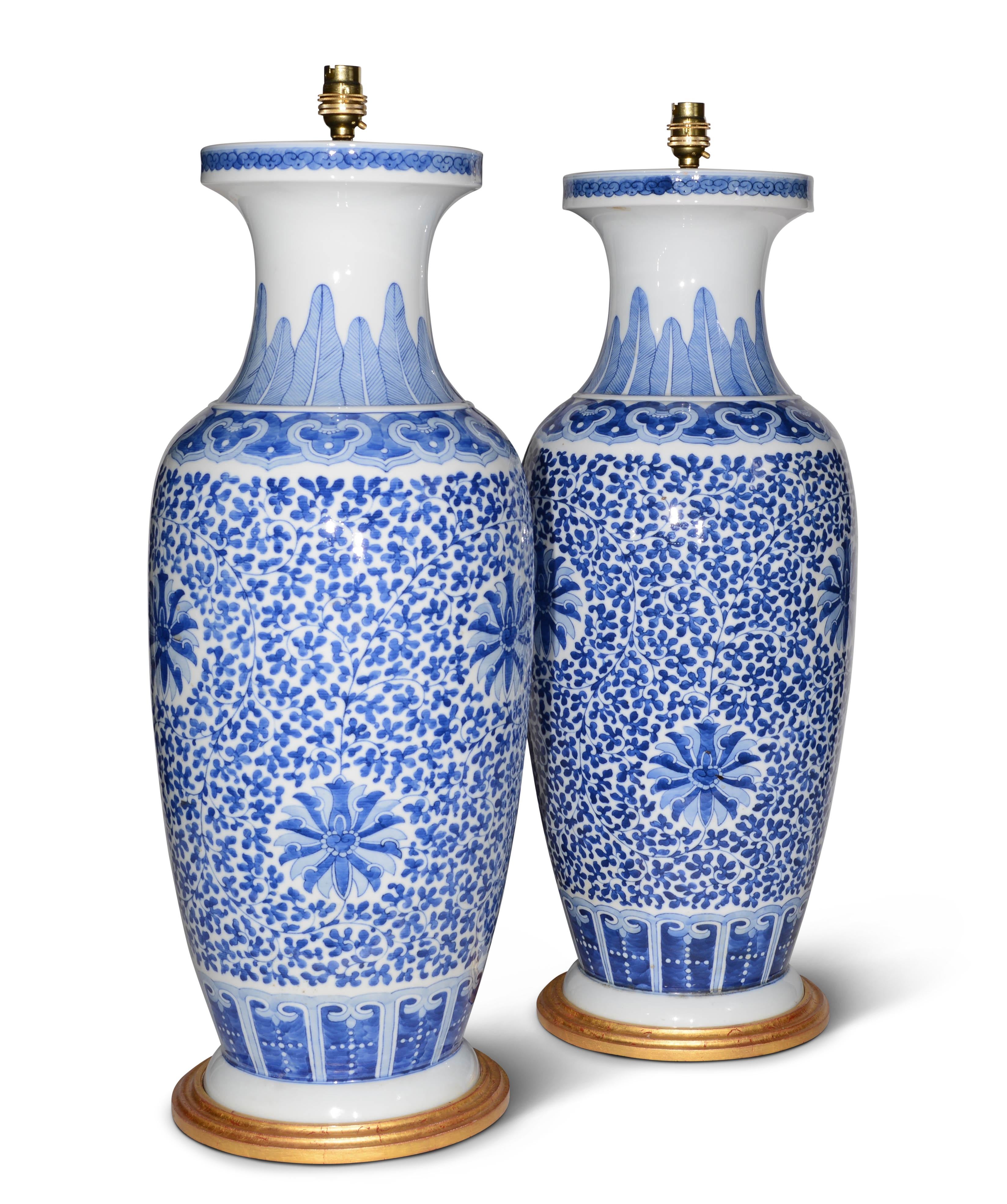 A fine pair of large Chinese blue and white baluster vases, decorated in tones of blue and whites in the Kangxi manner, now mounted as lamps with hand gilded turned bases.

Height of vases: 24 1/4 in (62 cm) including giltwood bases, excluding