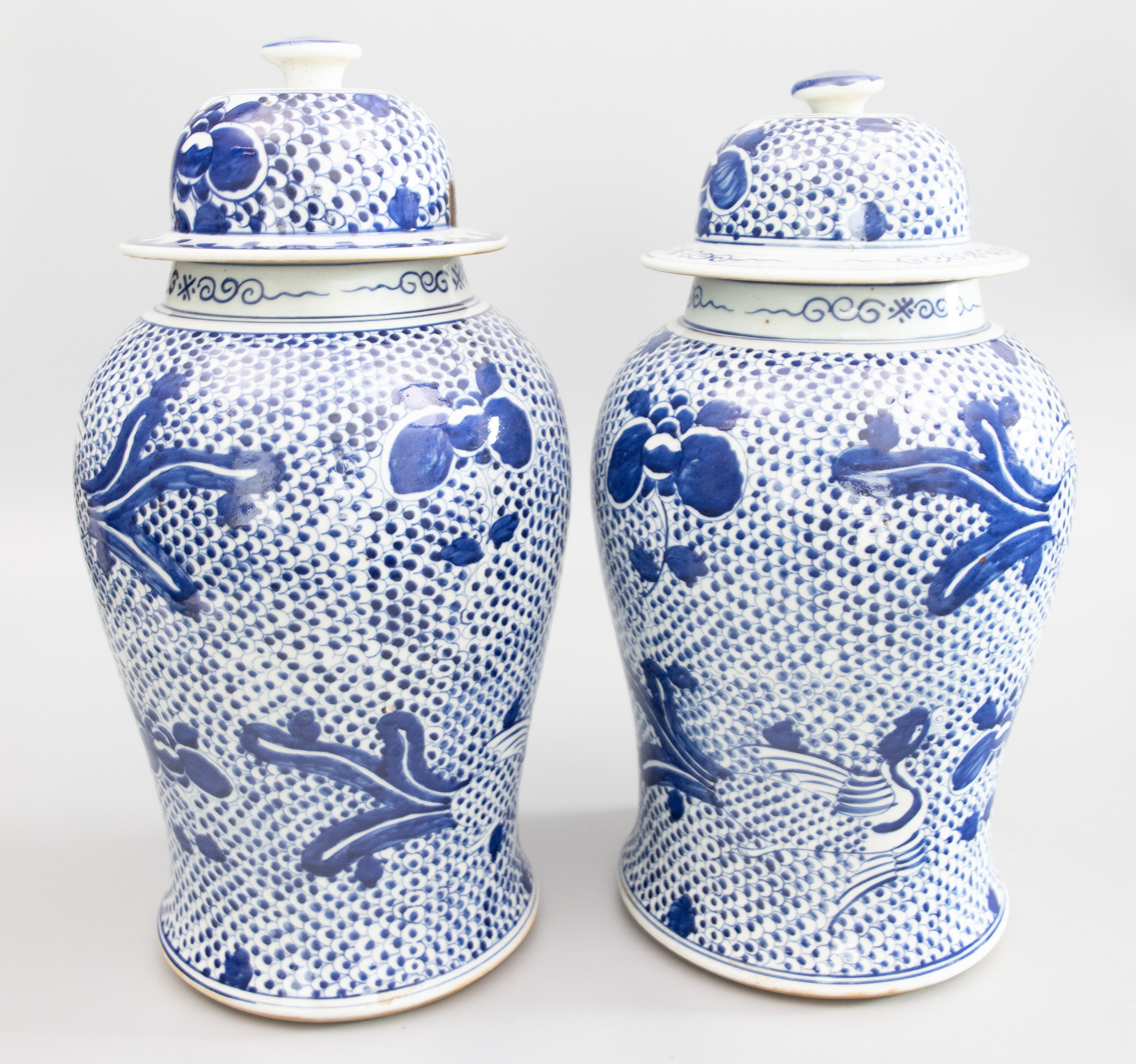 A lovely antique pair of Chinese Kangxi style handmade lidded temple jars or ginger jars. These stunning jars are a nice large size with hand painted phoenix birds and peony flowers over a vibrant cobalt blue and white Balasta pattern. There are