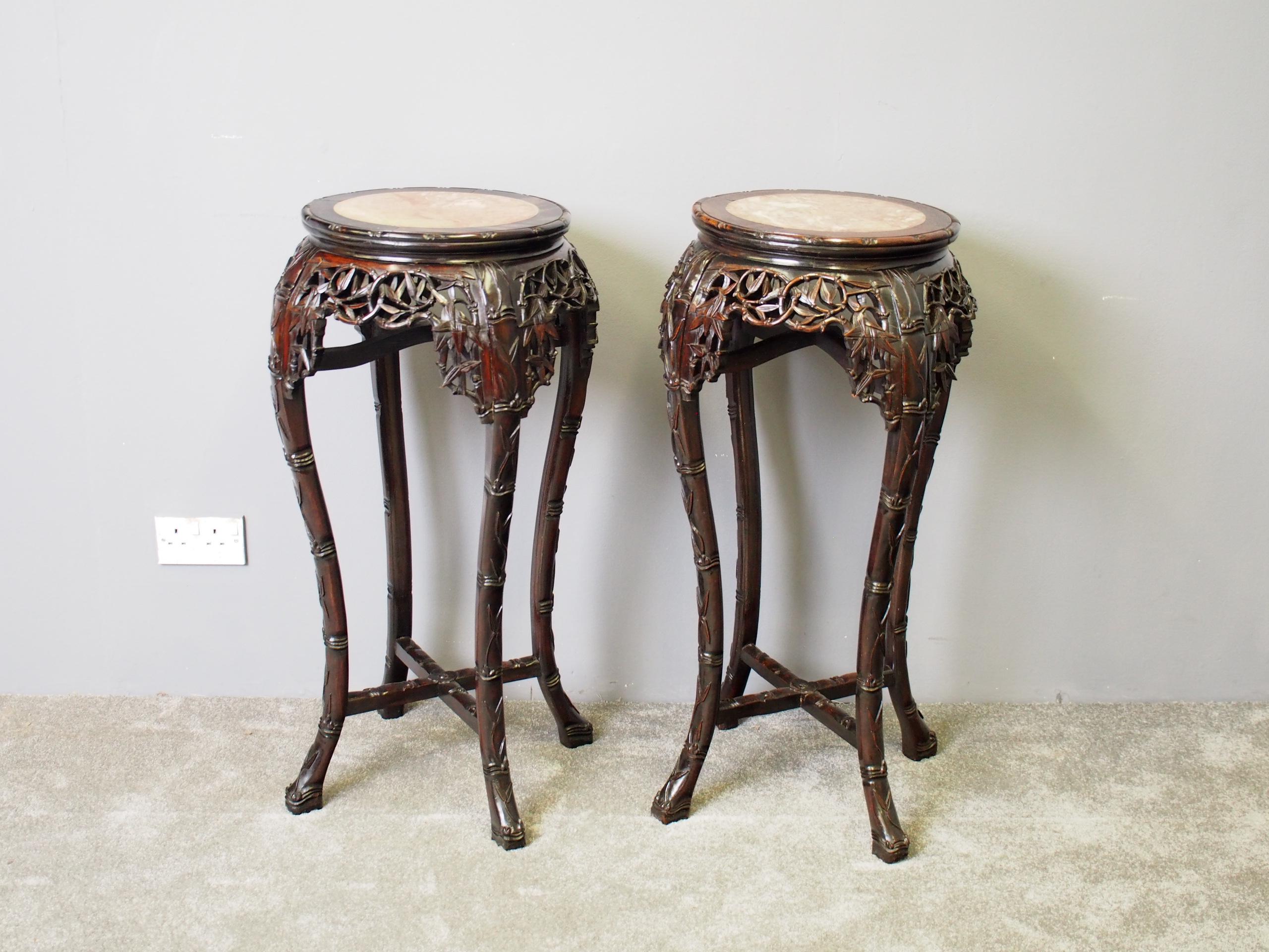 Rare pair of large Chinese rosewood plant stands, circa 1890. The circular tops with carved rims and variegated pink marble insets are over a convex, faux-bamboo carved, elaborate open fretwork frieze. This is supported on four foliate-carved