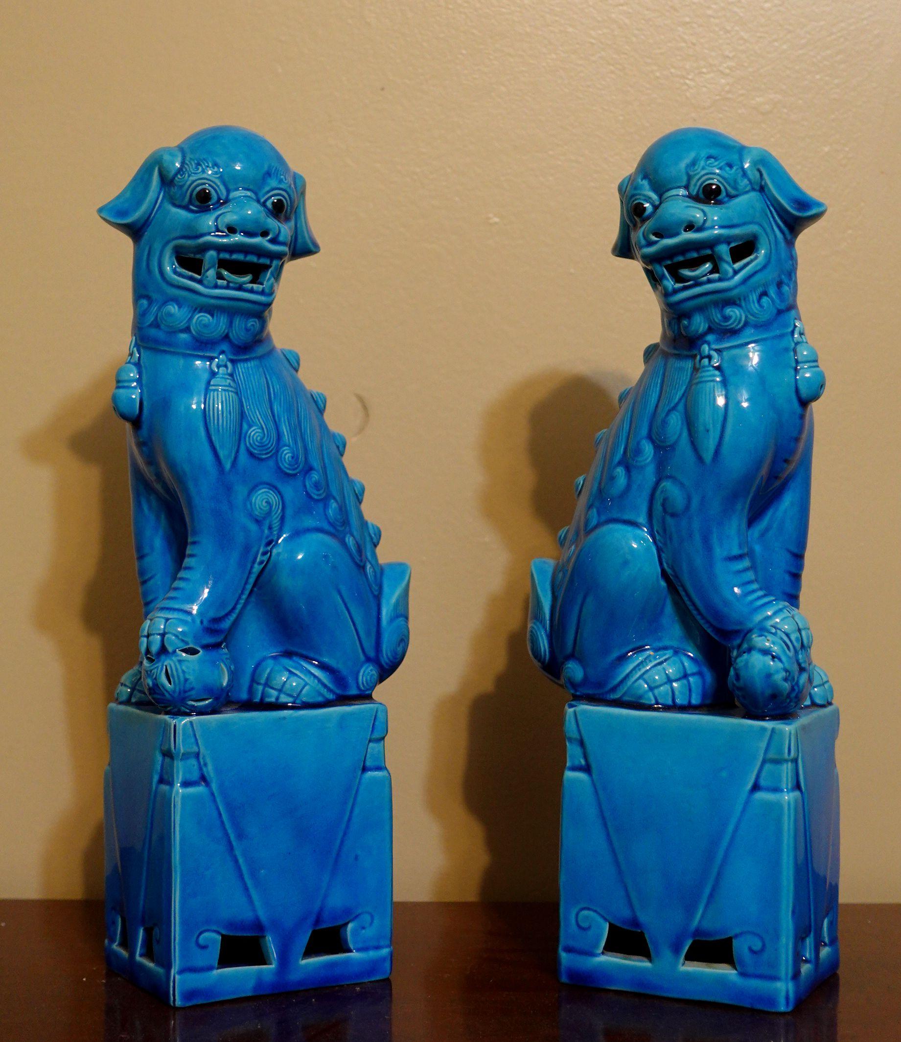 Fine and very detailed pair of Chinese turquoise glazed foo dogs from the mid-20th century. The hollow biscuit porcelain figures stand raised on a rectangular base and are looking sideways with open mouths and tongues showing teeth each with a