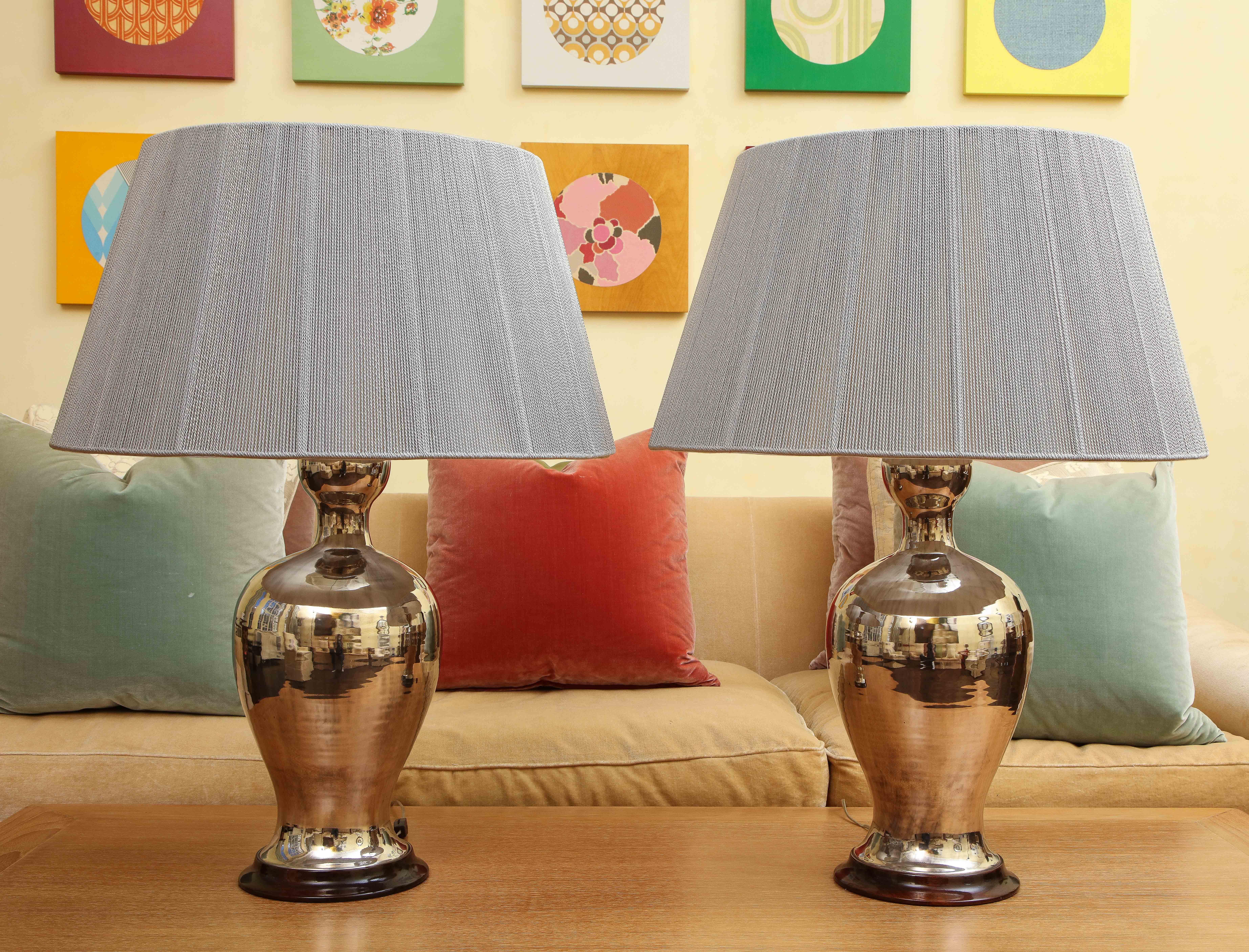 Pair of extra-large custom-made table lamps by Christopher Spitzmiller. Timeless shaped ceramic body with silver lustre glaze and hardwood base. Grey string lamp shades are included, interior torn as shown. Brass double socket, wired for USA.