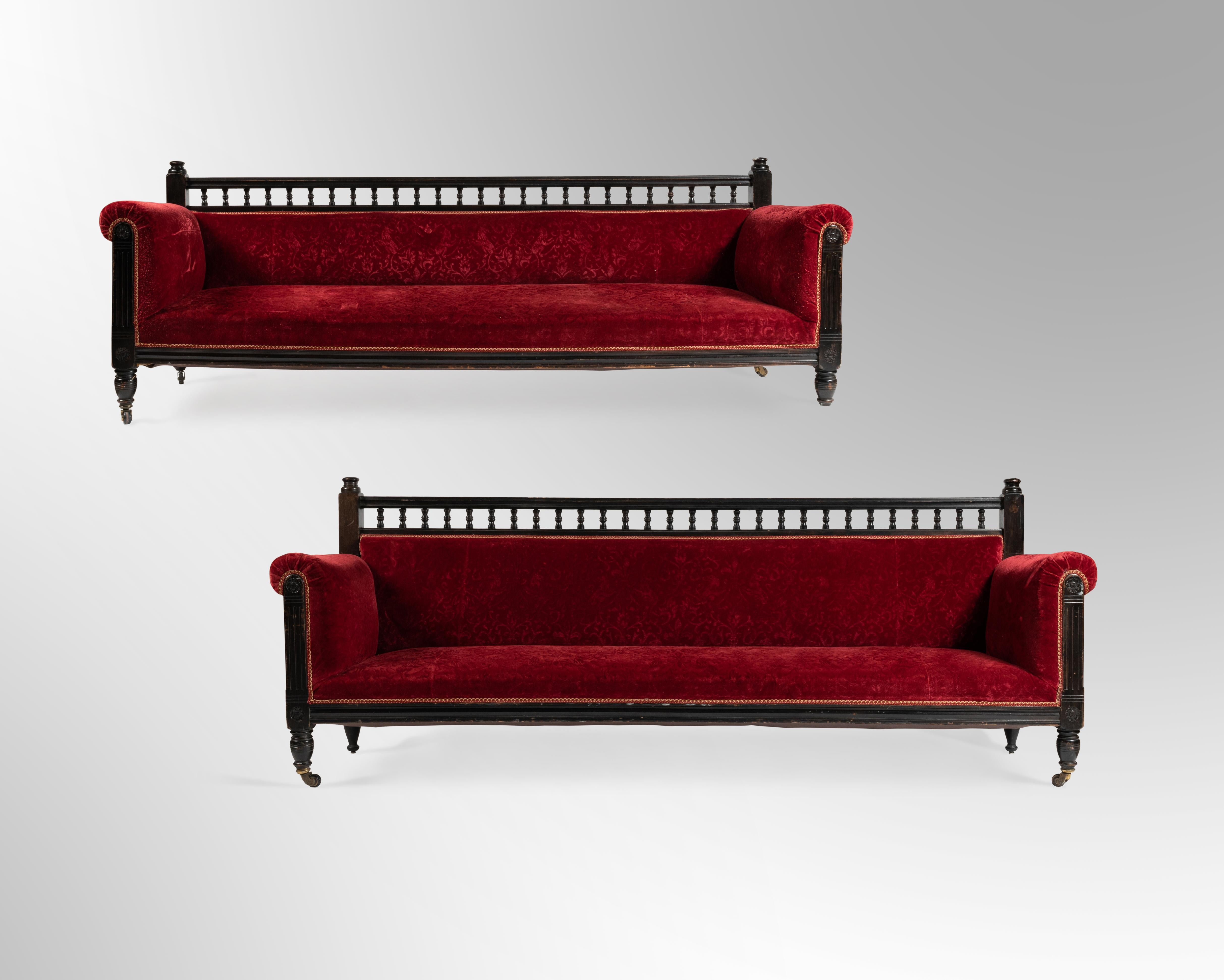 Aesthetic movement. Pair of large sofas in turned and blackened wood, decorated with balusters, covered in red embossed velvet. Circa 1880.